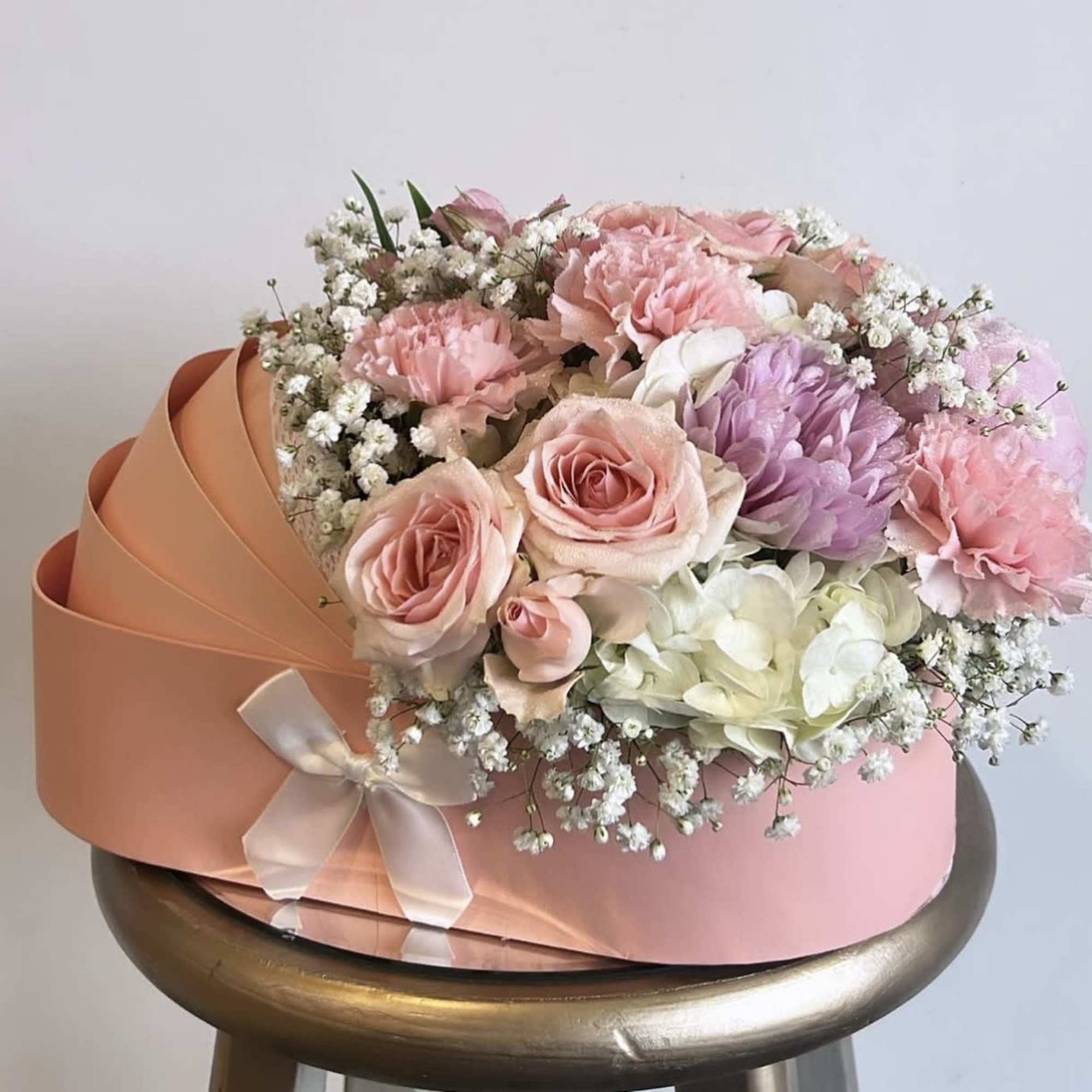 Pink and white bouquet with roses, carnations, and hydrangeas in peach wrapping