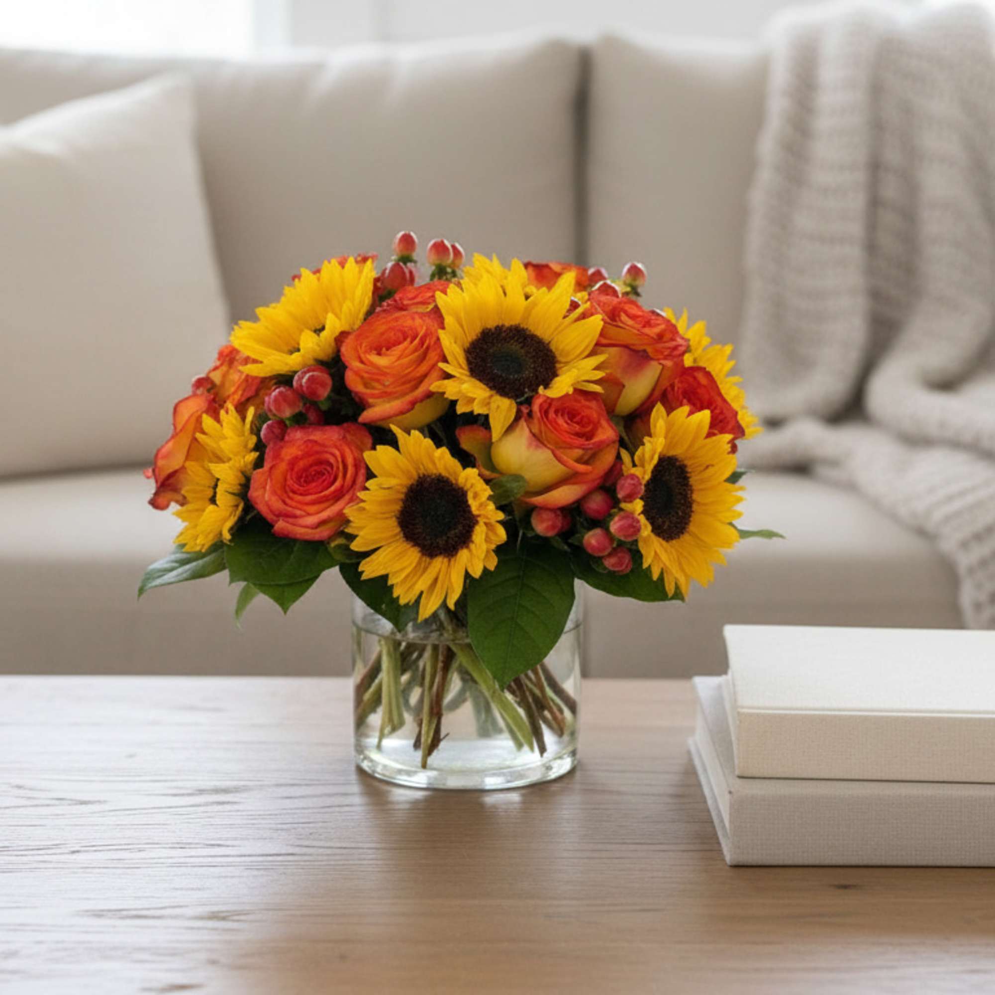 Bouquet of sunflowers and orange roses in a clear glass vase