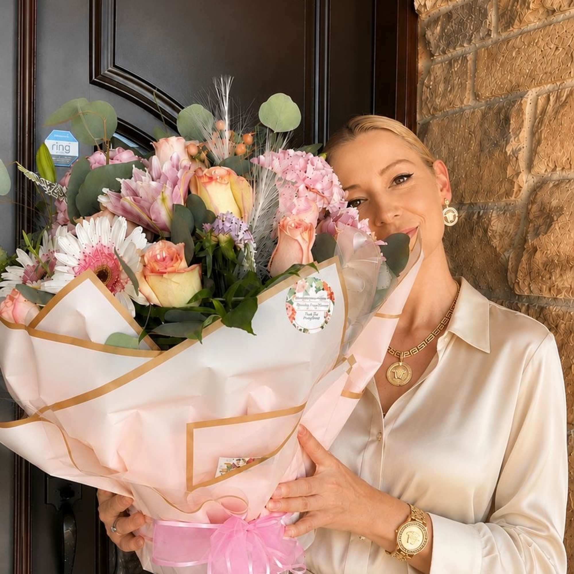 Woman holding a large pastel bouquet wrapped in pink paper with a ribbon