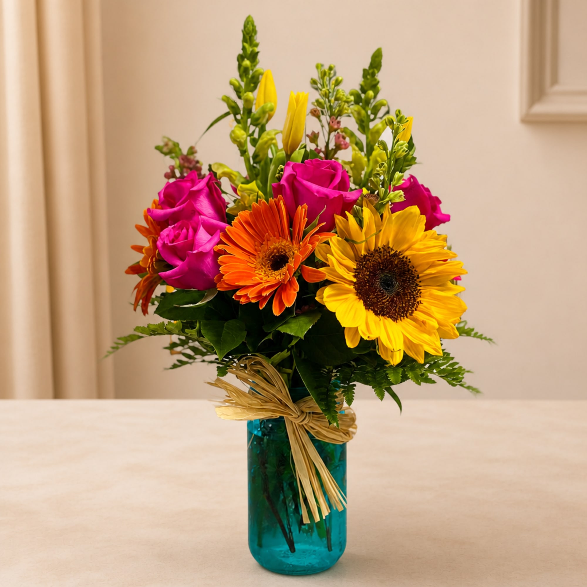 Bright mixed bouquet with roses, gerbera daisies, and sunflowers in a blue vase