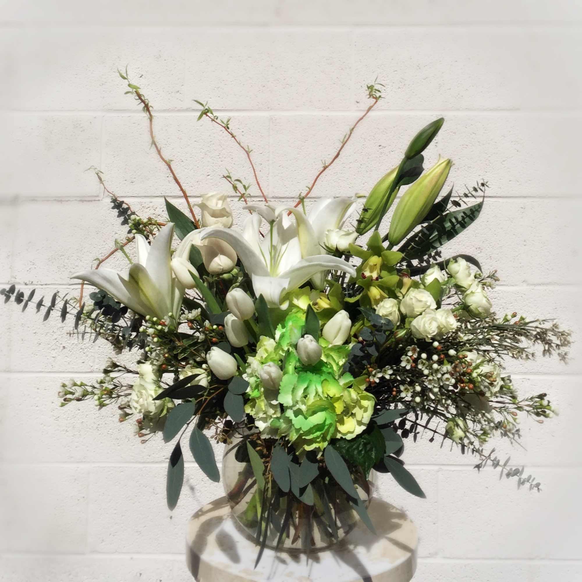 White lilies and green hydrangeas in a glass vase