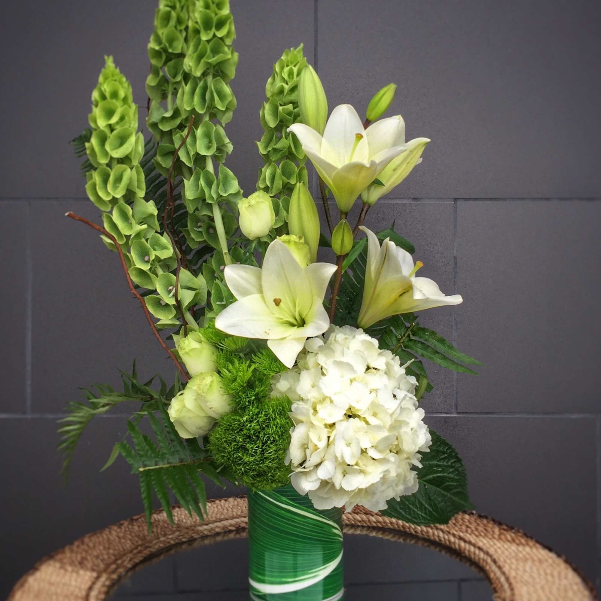 Fresh design including Bells of Ireland, hydrangea, lily, rose... and accents. 
STANDARD: