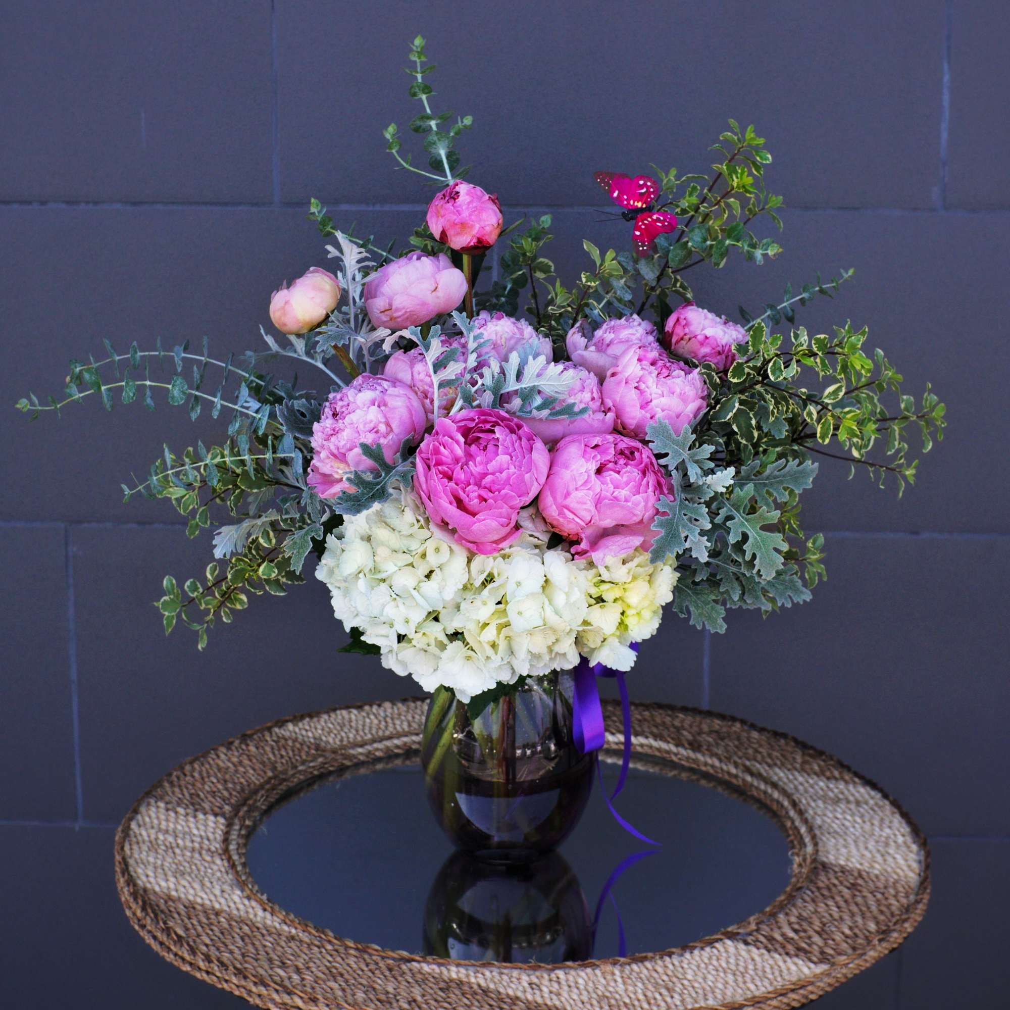Pink peonies and white hydrangeas in a dark glass vase