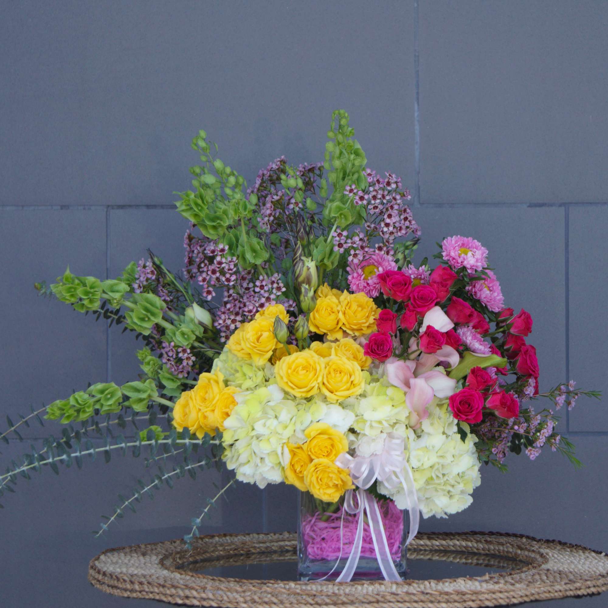 Mixed bouquet of yellow, pink, and white flowers in a glass vase