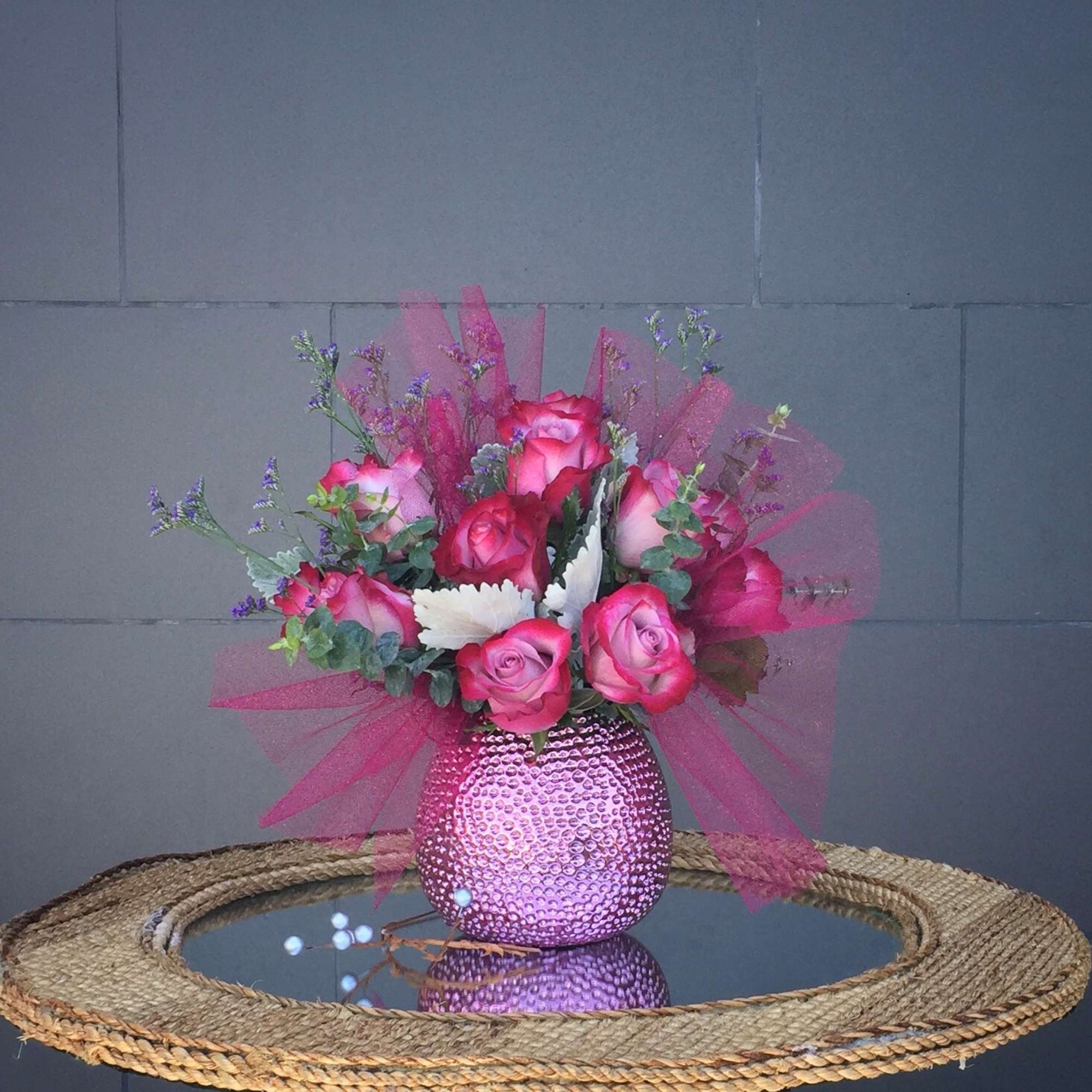 Pink rose bouquet in a textured pink vase with tulle wrap