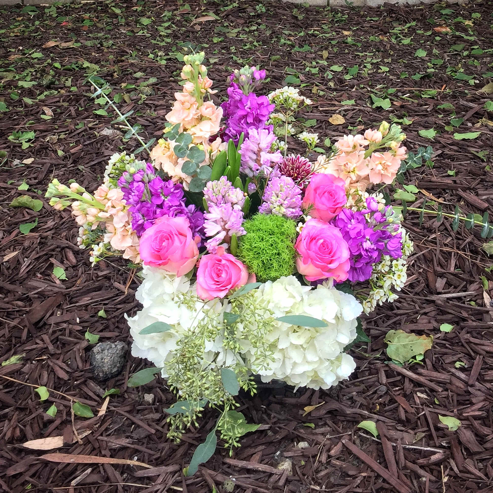 Colorful floral arrangement with pink roses, purple blooms, and white hydrangeas