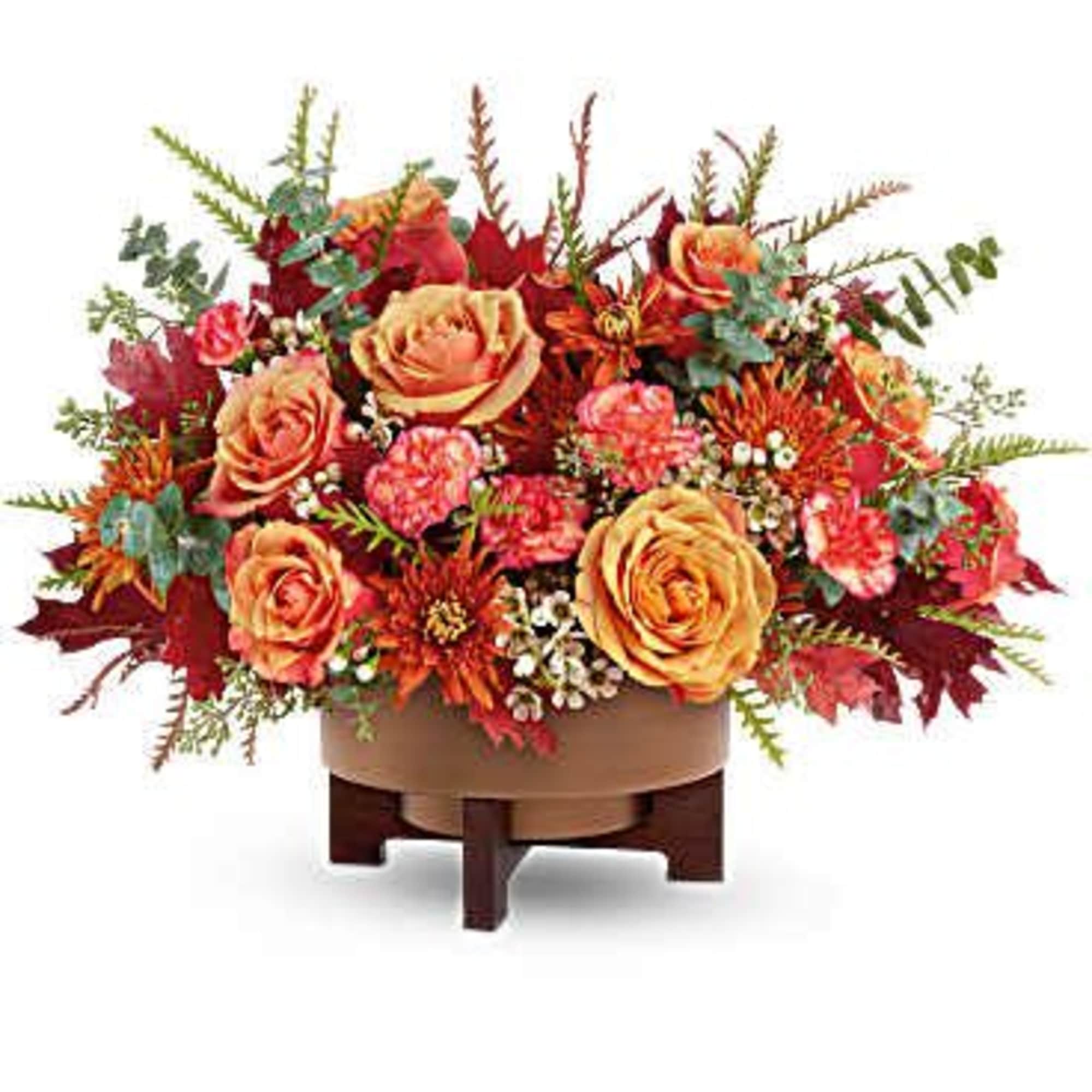 Autumn floral arrangement with orange roses in a low wooden container