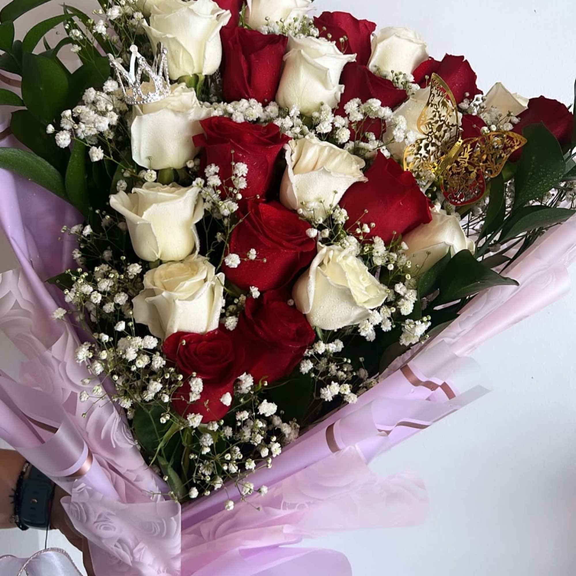 Bouquet of red and white roses wrapped in pink paper with baby’s breath