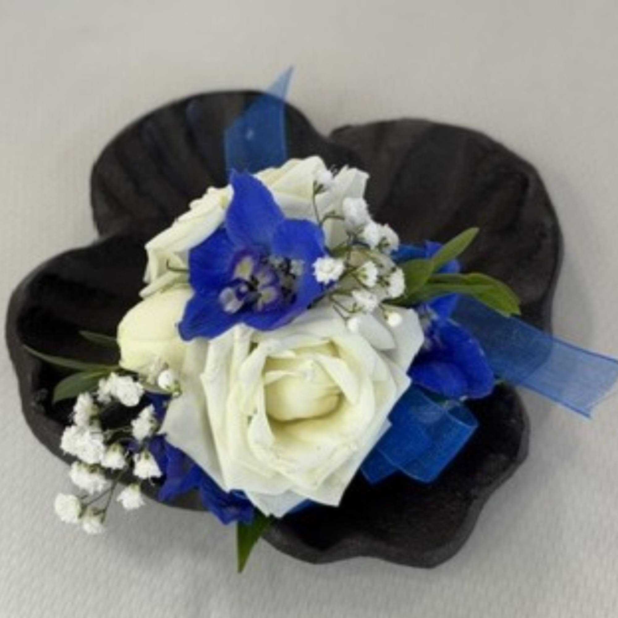 White roses with blue flowers in a black corsage