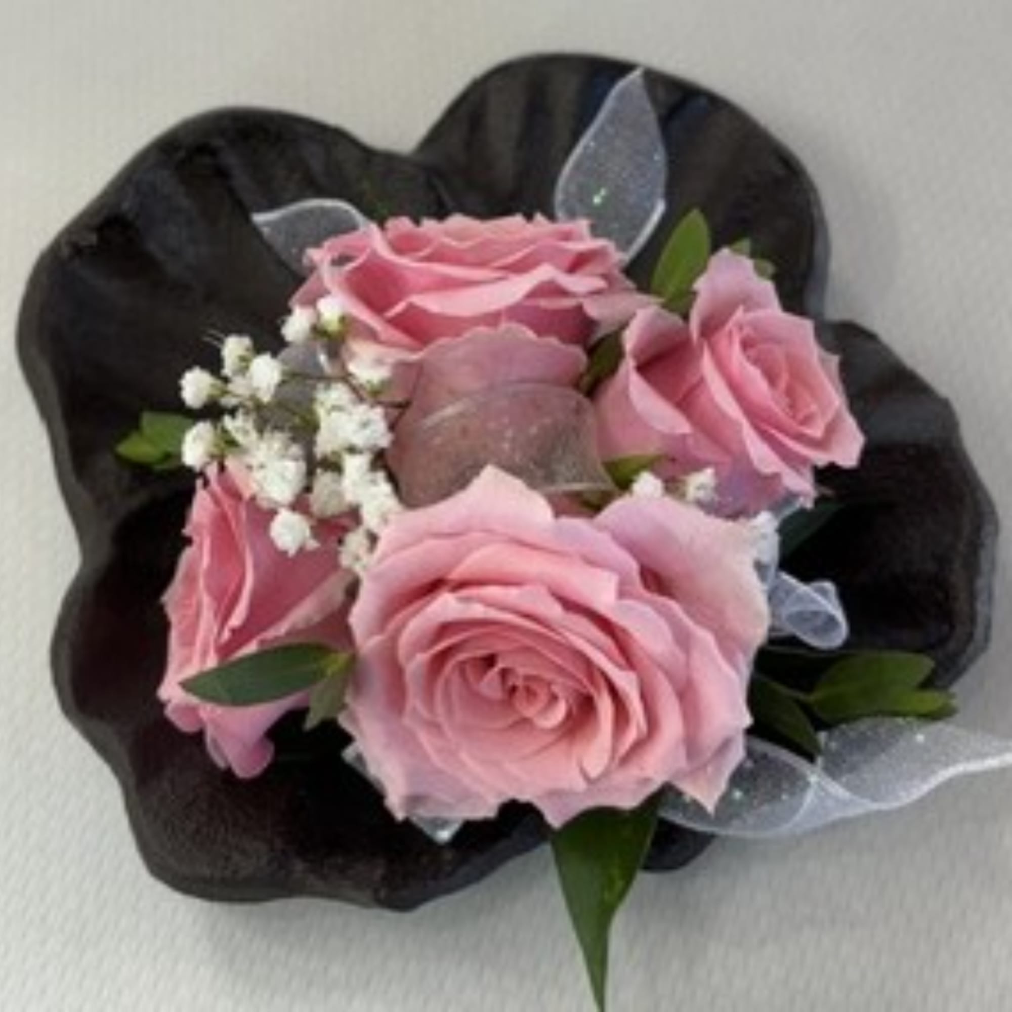 Pink rose boutonniere with baby's breath on a black wrap