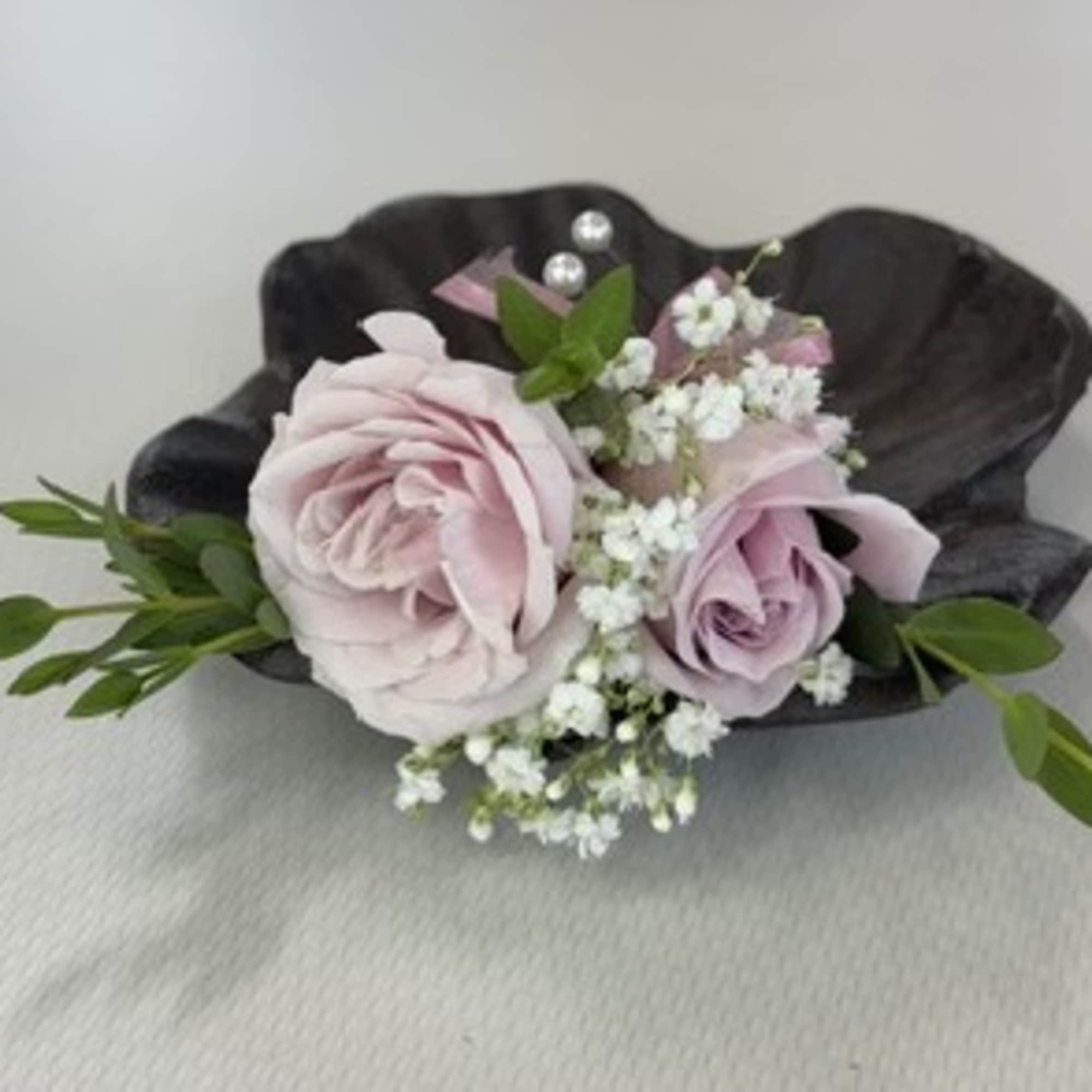 Small corsage with pale pink roses and white baby's breath on a dark shell