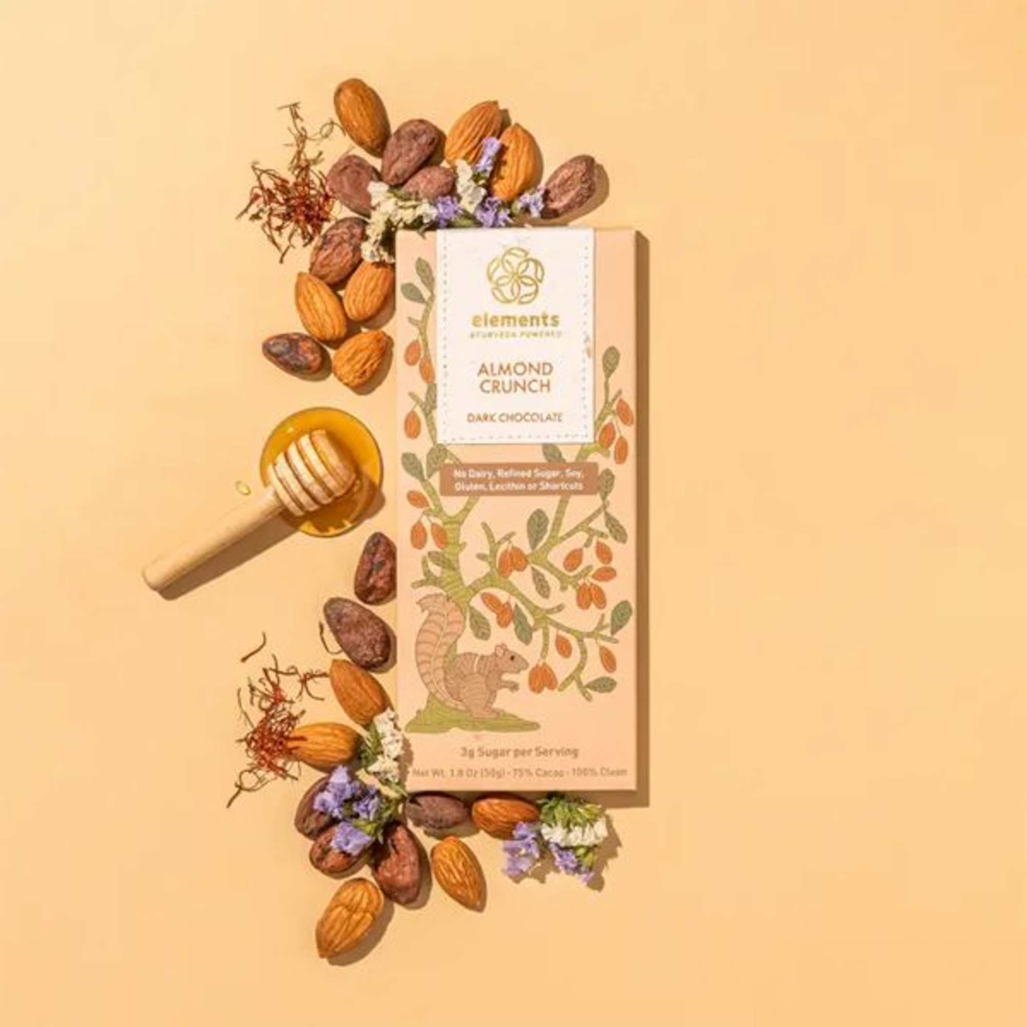 Chocolate bar with almonds, honey dipper, and scattered nuts on a peach background