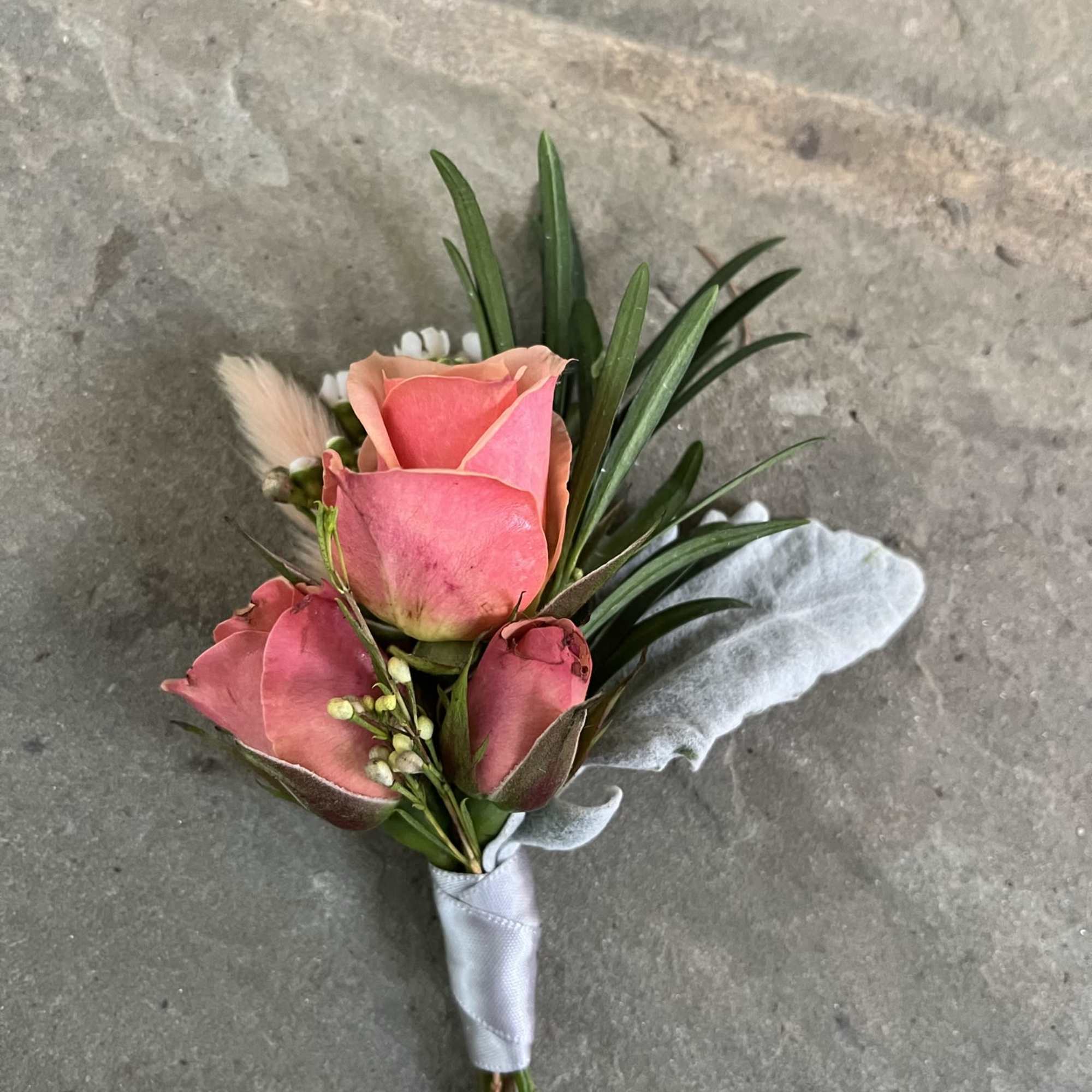 Small pink rose boutonniere with ribbon wrap and greenery