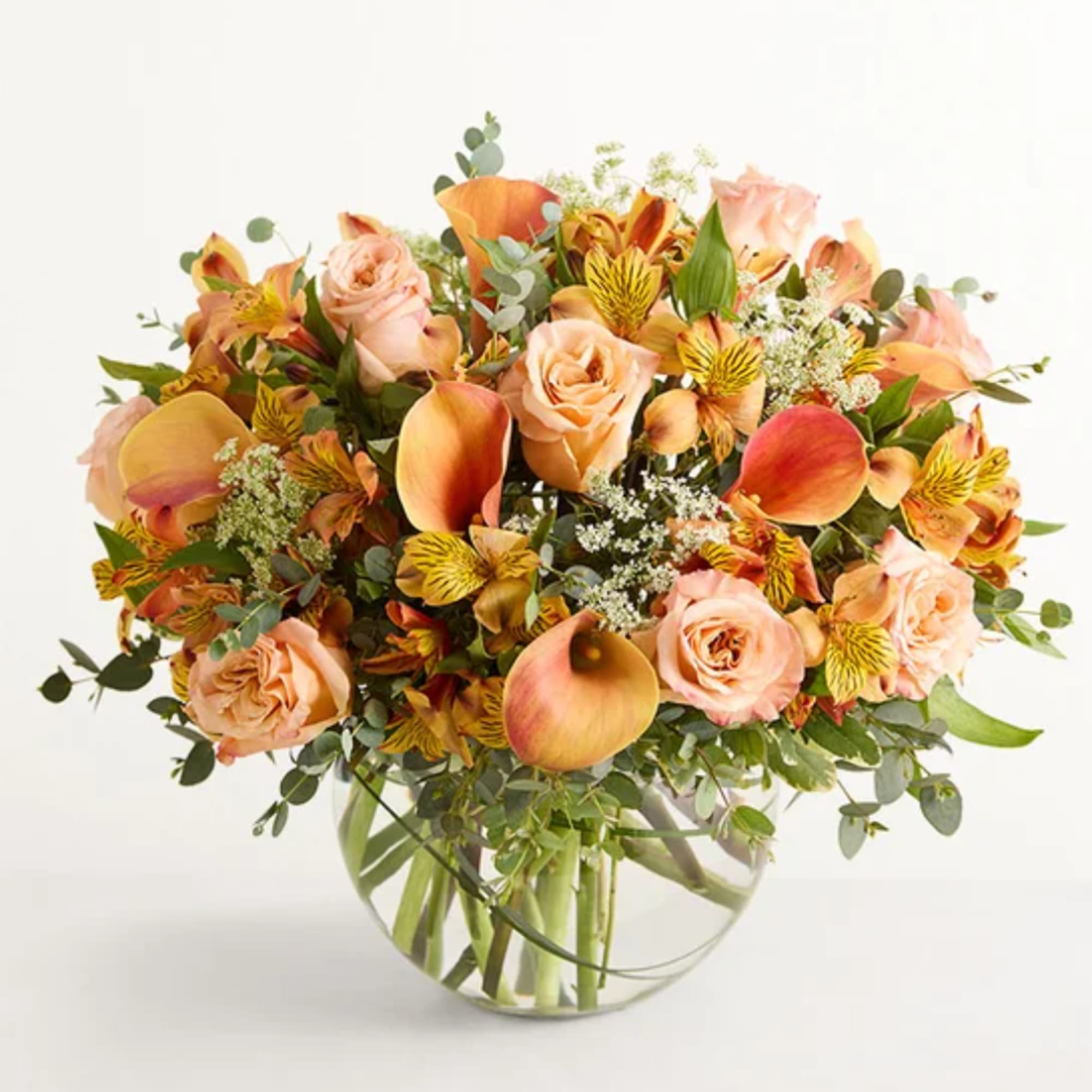 Peach roses and orange calla lilies in a clear glass vase