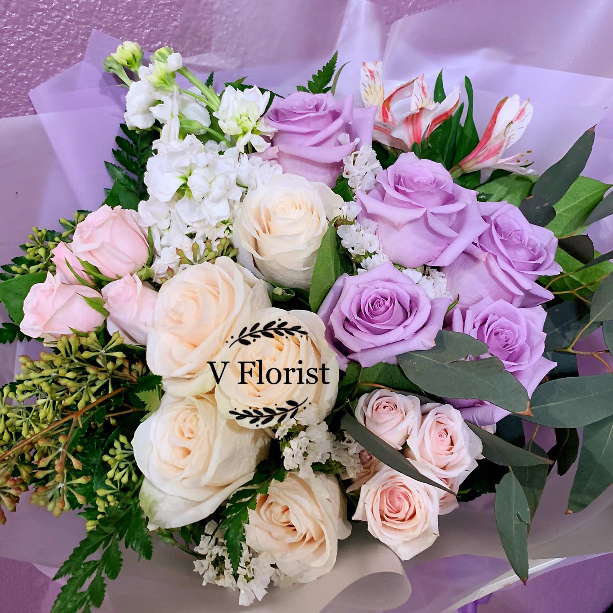 Bouquet of lavender, pink, and cream roses with white blooms