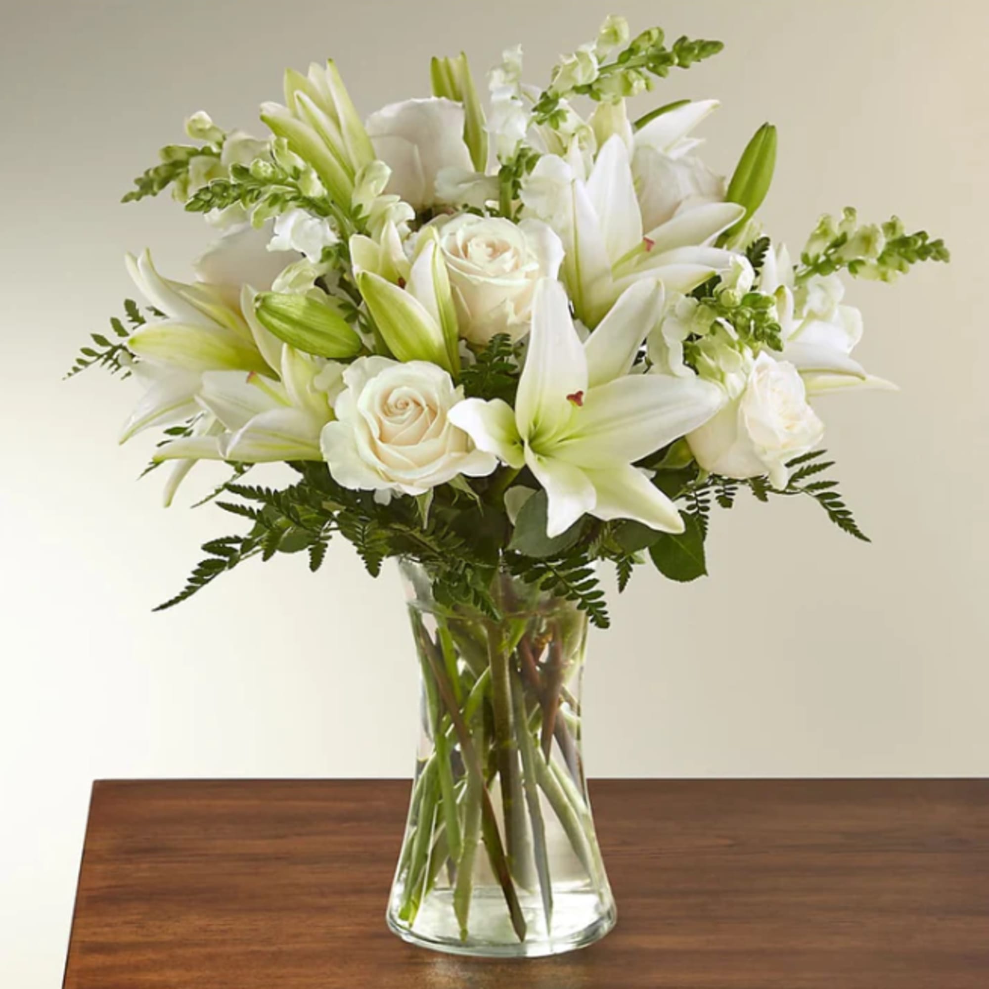 White lilies and roses arranged in a clear glass vase