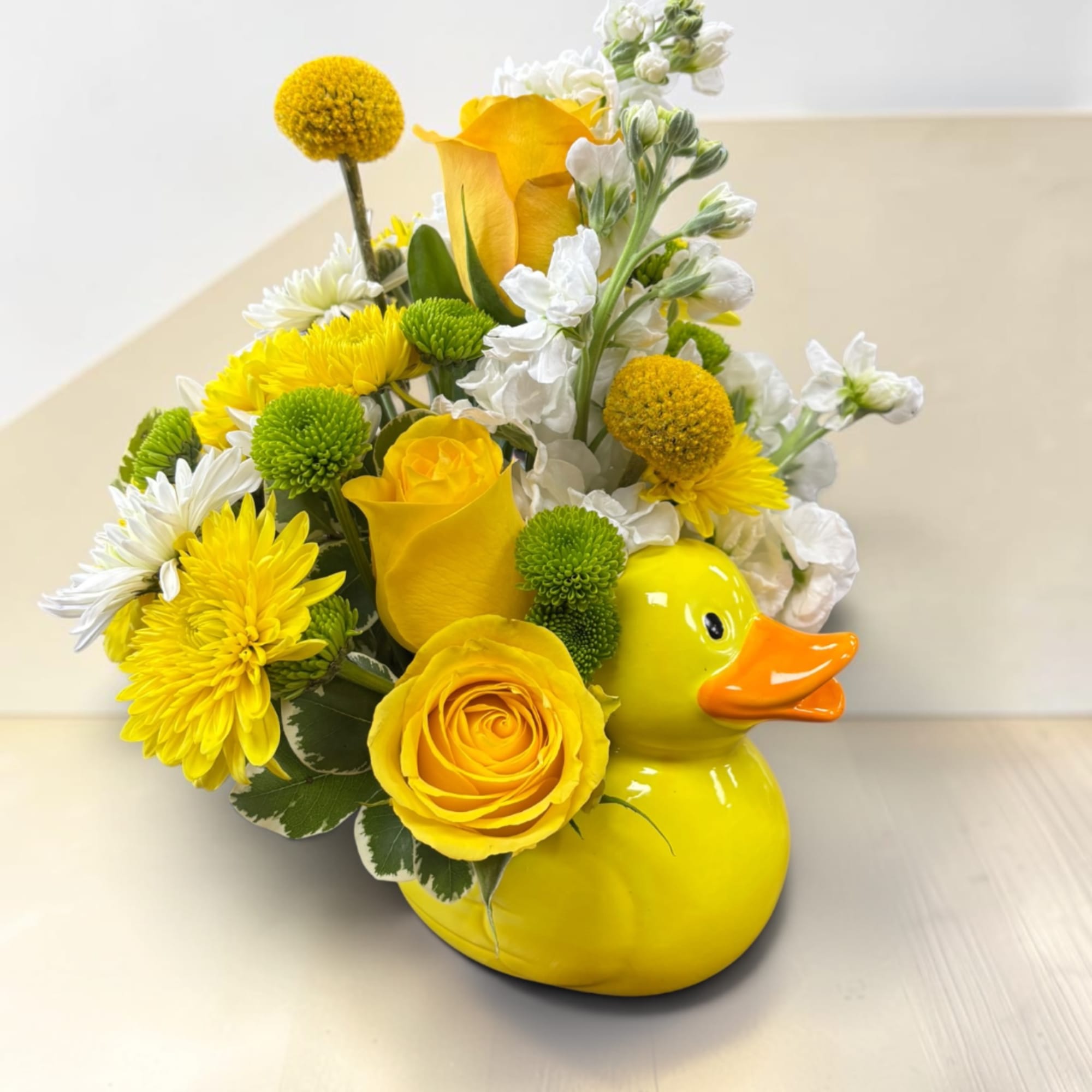 Yellow floral arrangement in a duck-shaped ceramic container