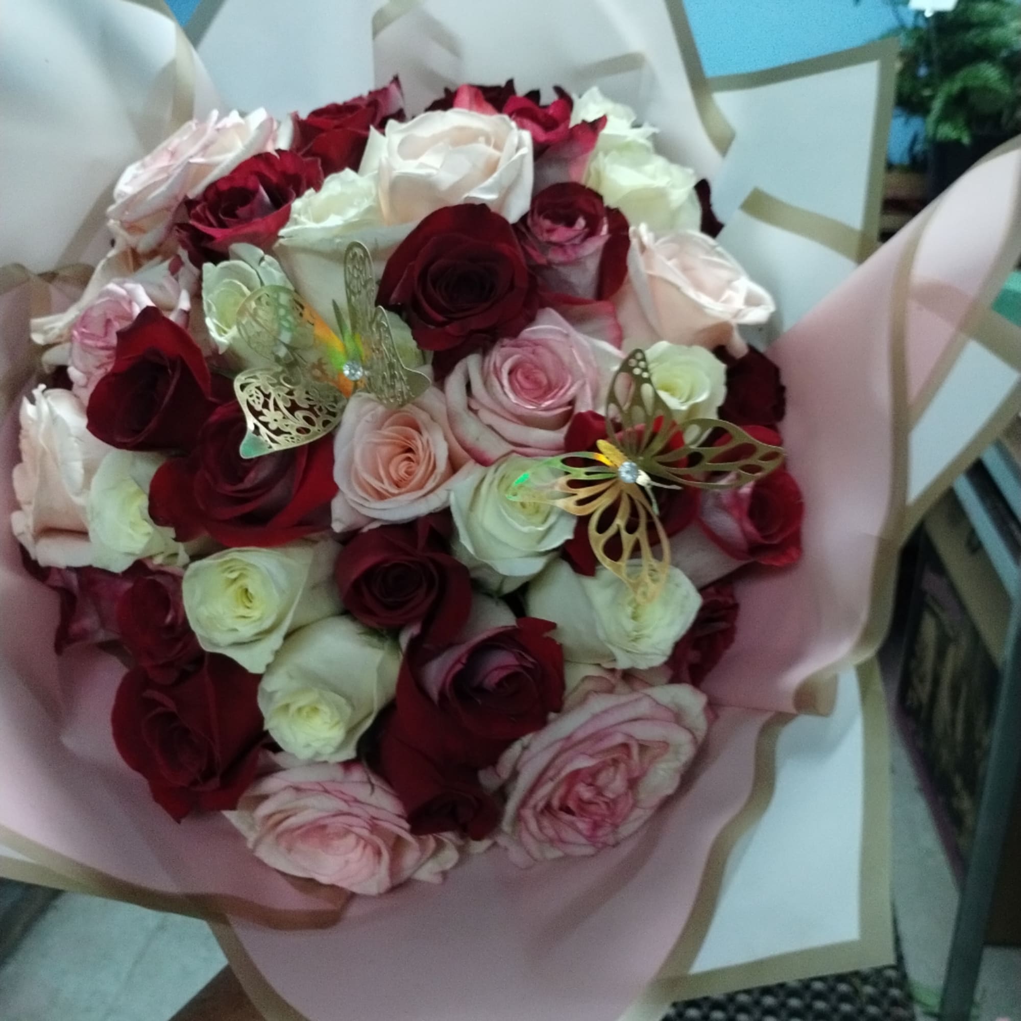 Bouquet of red, pink, and white roses wrapped in pink paper
