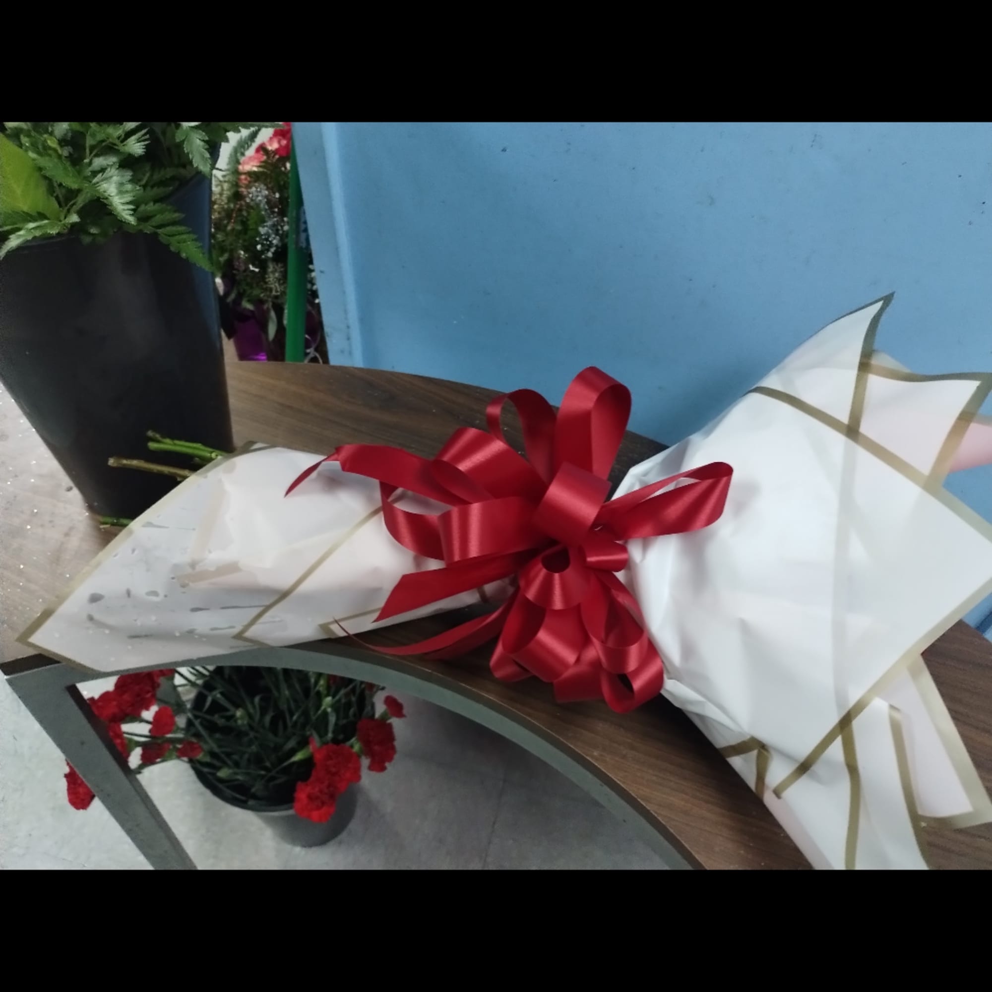 Wrapped bouquet with a red ribbon on a table