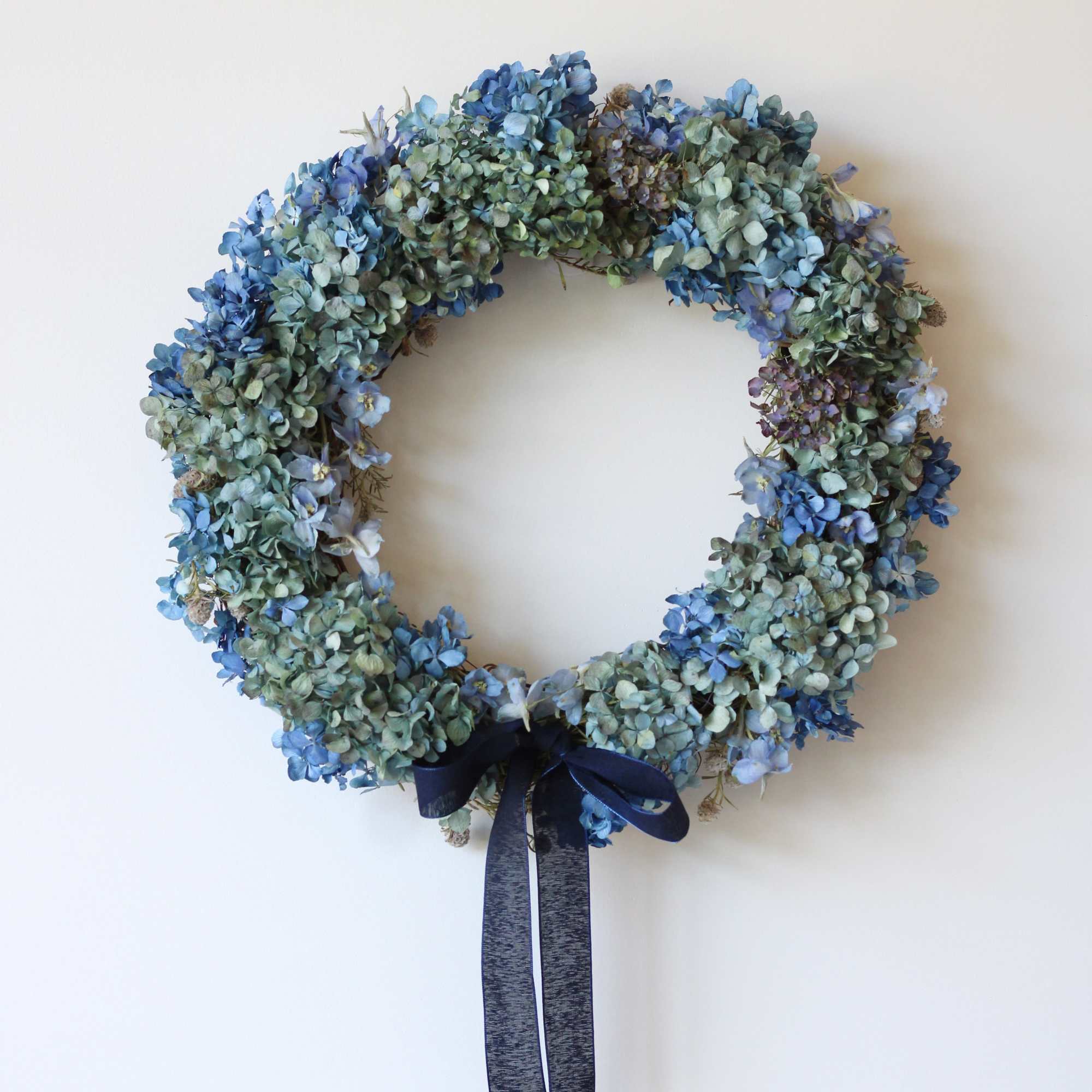 Blue dried flower wreath with a dark ribbon bow