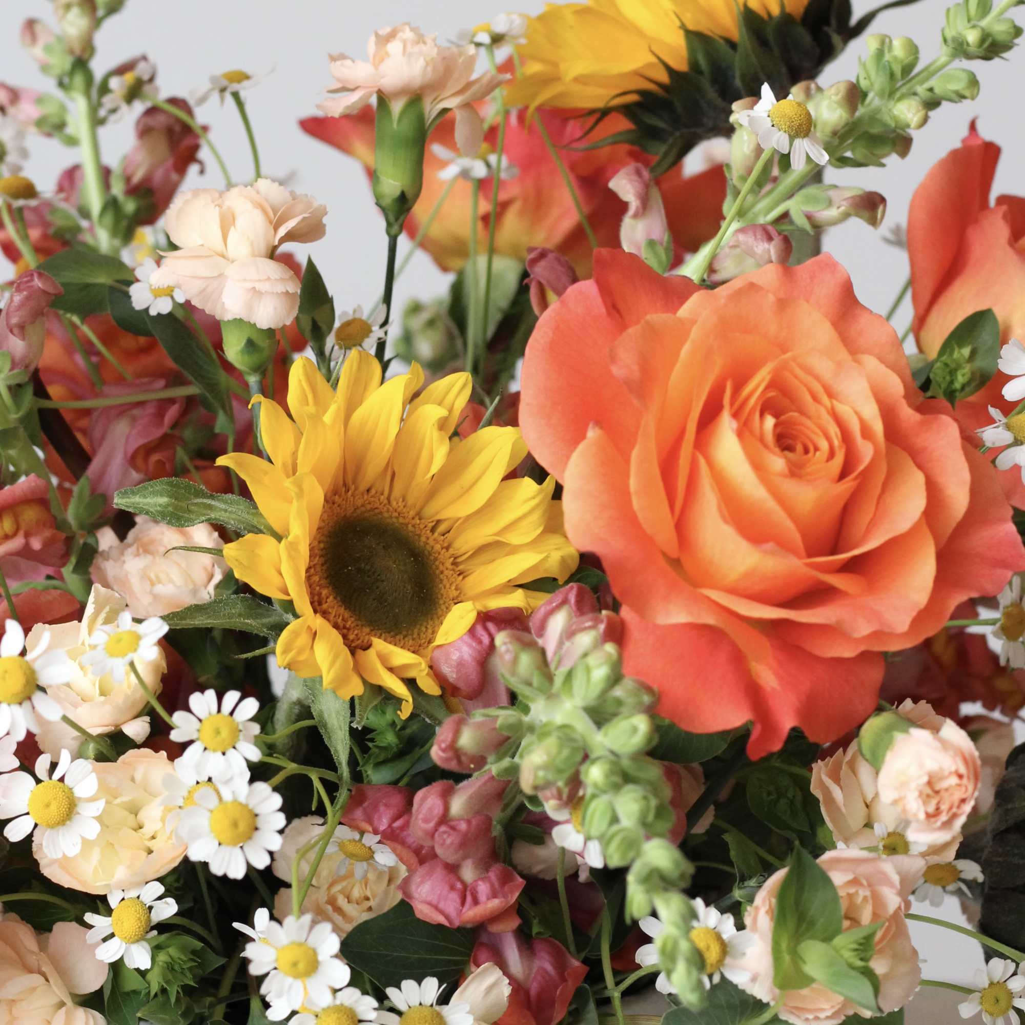 Mixed bouquet with orange roses, sunflowers, and small white daisies