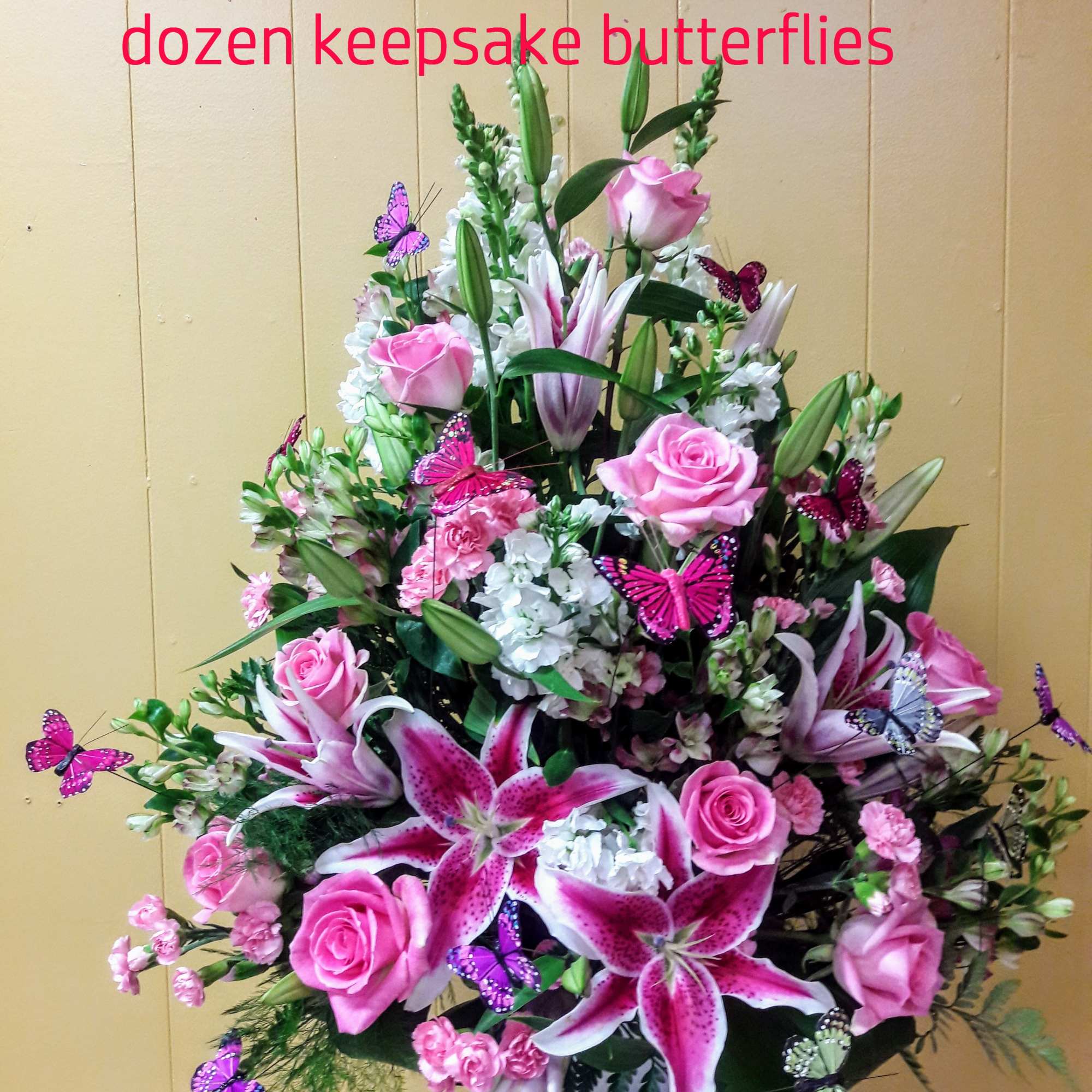 Pink roses and lilies in a white vase with decorative butterflies