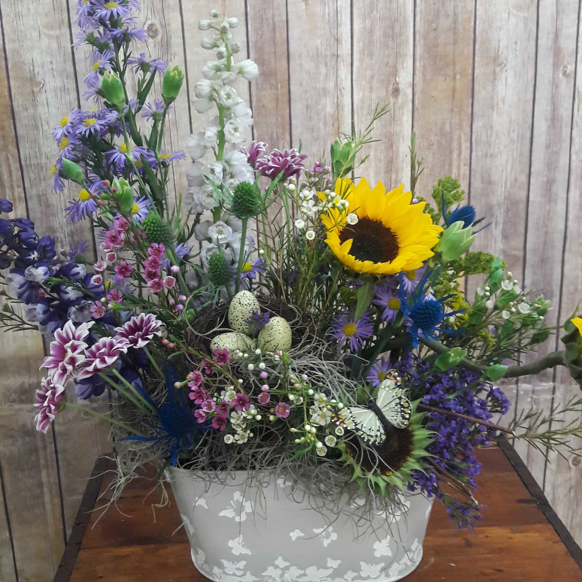 Mixed floral arrangement with sunflowers in a white container
