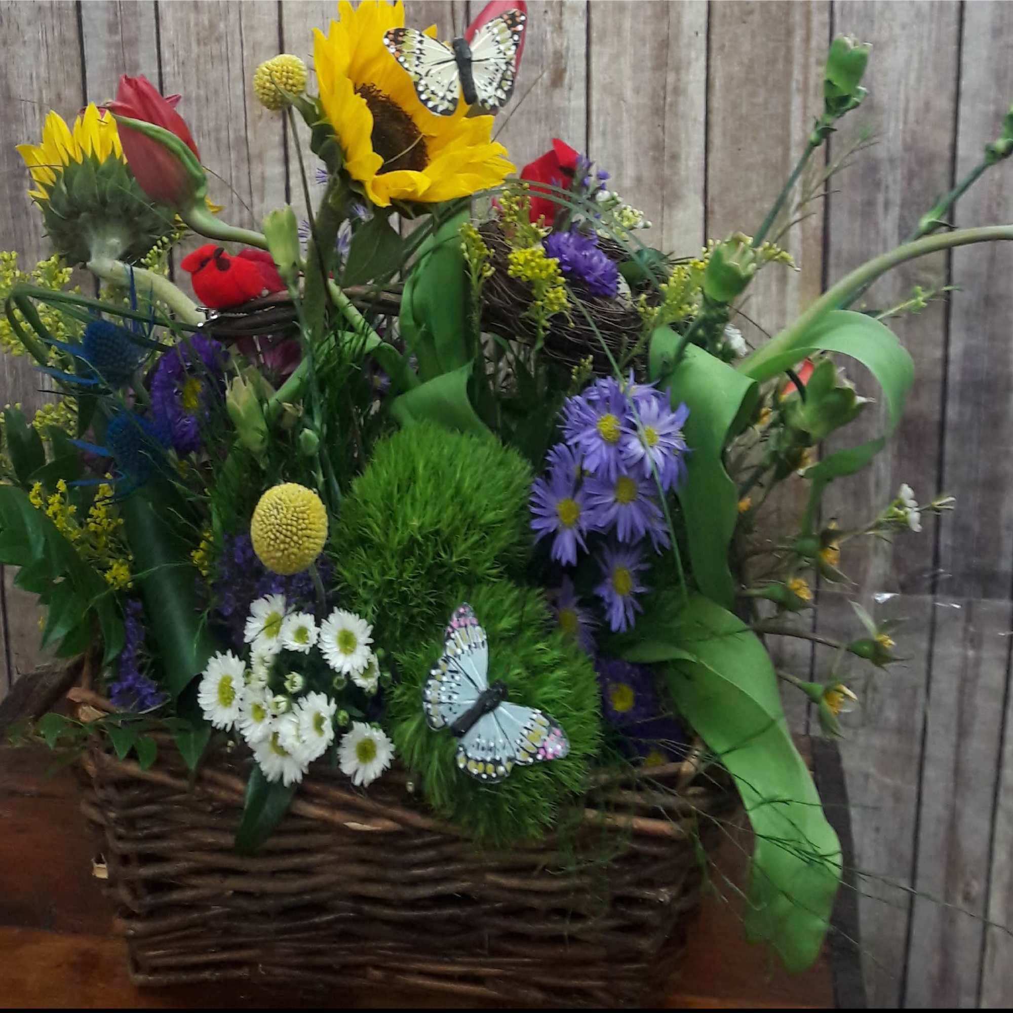 Mixed bouquet in a wicker basket with sunflowers, tulips, and daisies