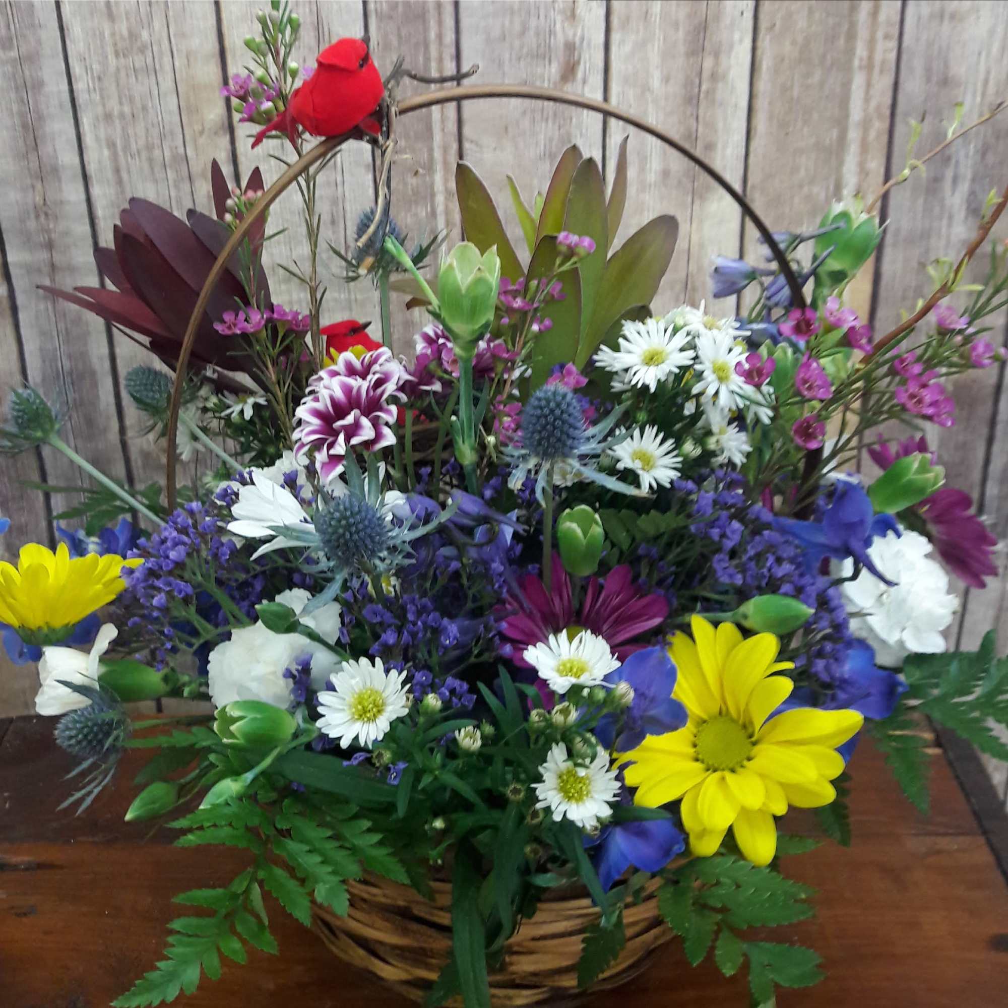 Mixed bouquet in a basket with yellow daisies, white daisies, and purple flowers