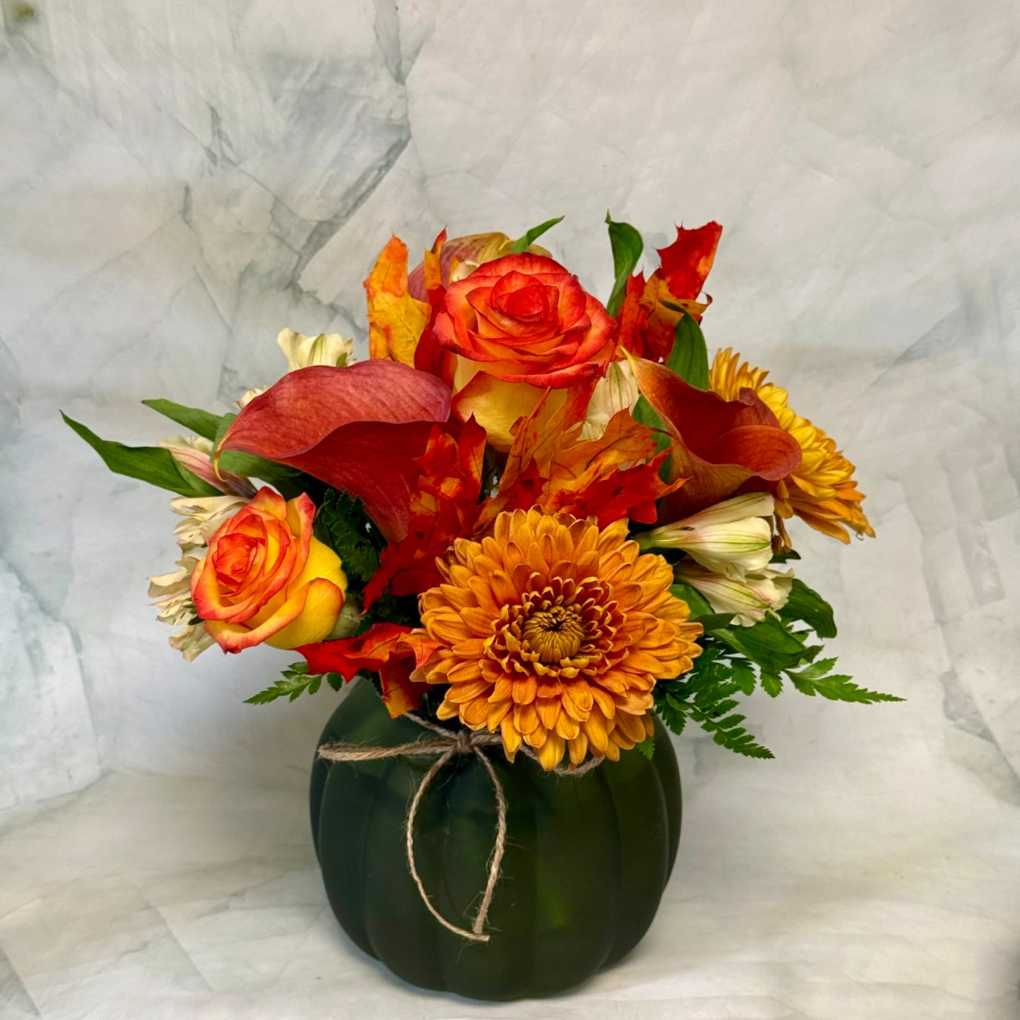 Autumn bouquet of orange roses and yellow chrysanthemums in a dark vase