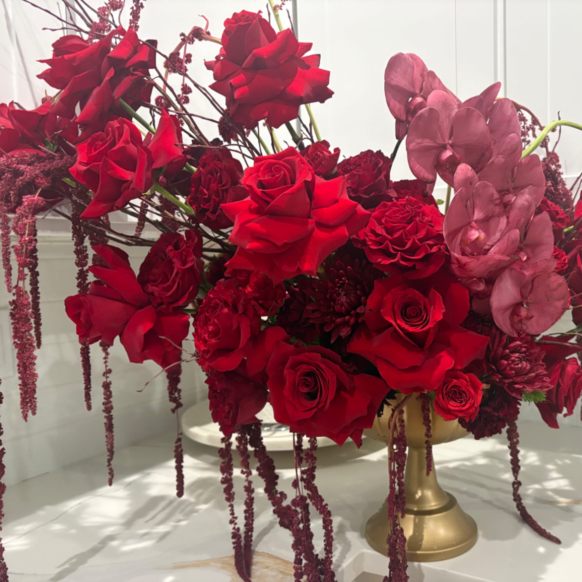 Red rose arrangement with pink orchids in a gold pedestal vase, photo 2 of 2