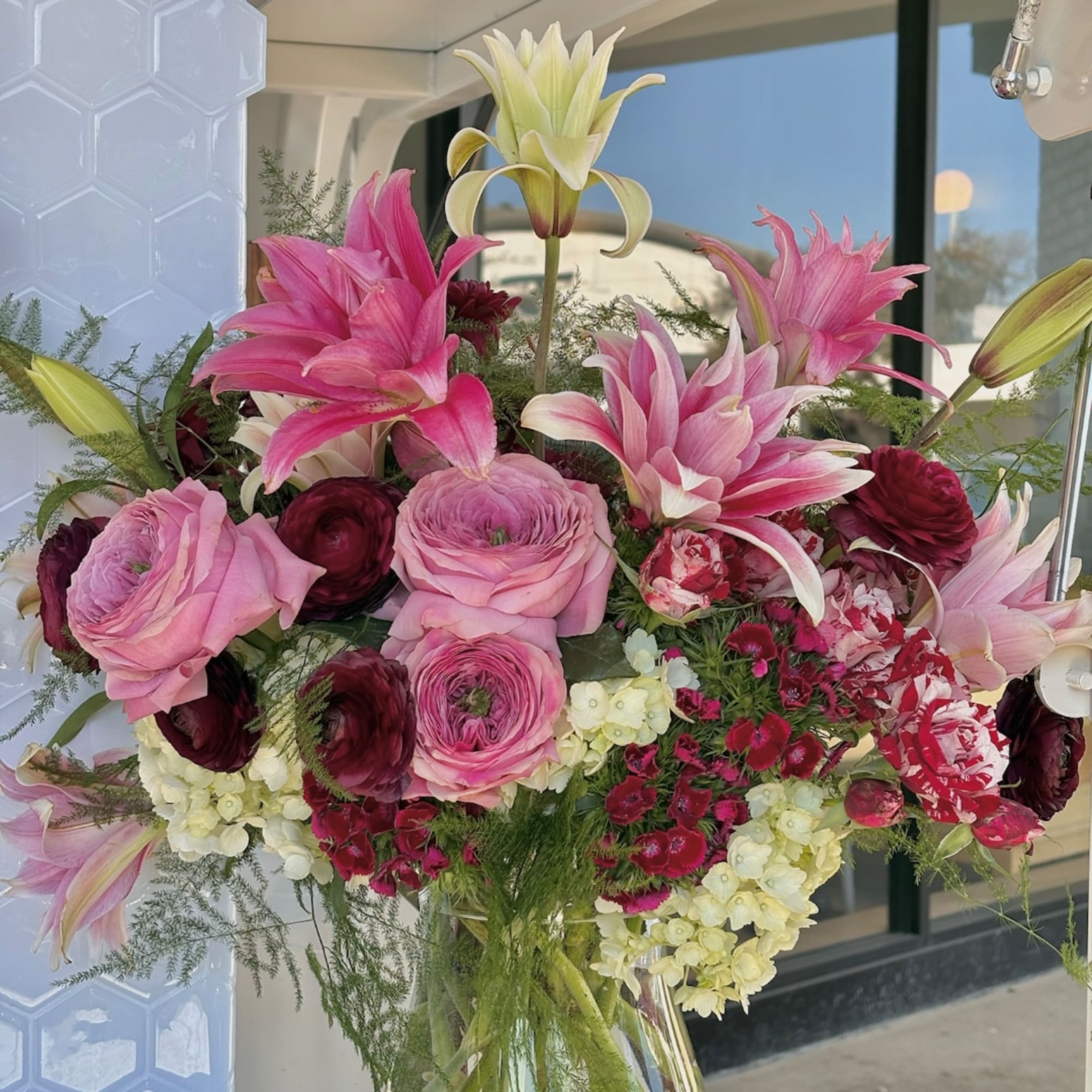 Pink lilies and roses arranged in a clear glass vase, photo 2 of 2