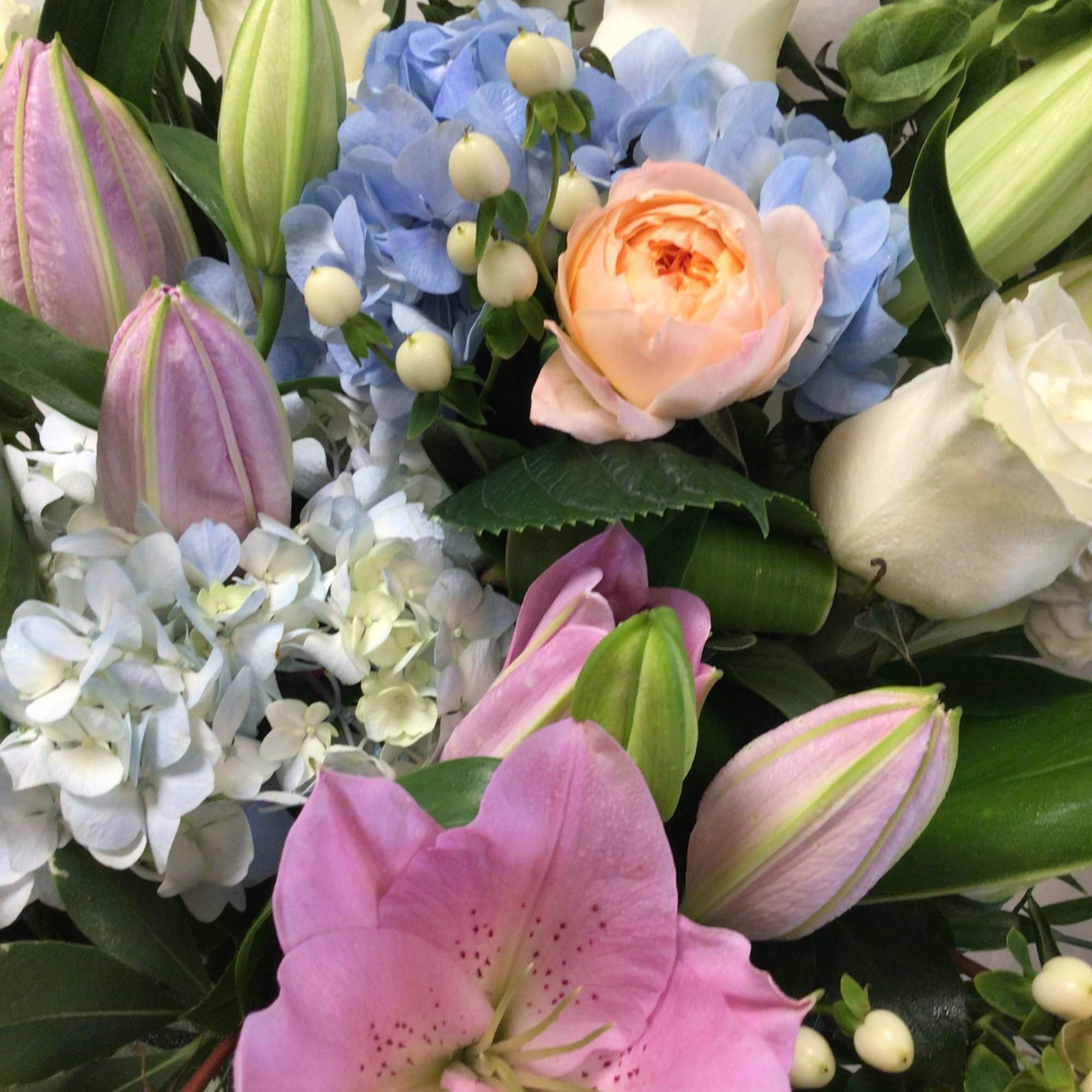 Mixed bouquet with pink lilies, blue hydrangeas, and cream roses