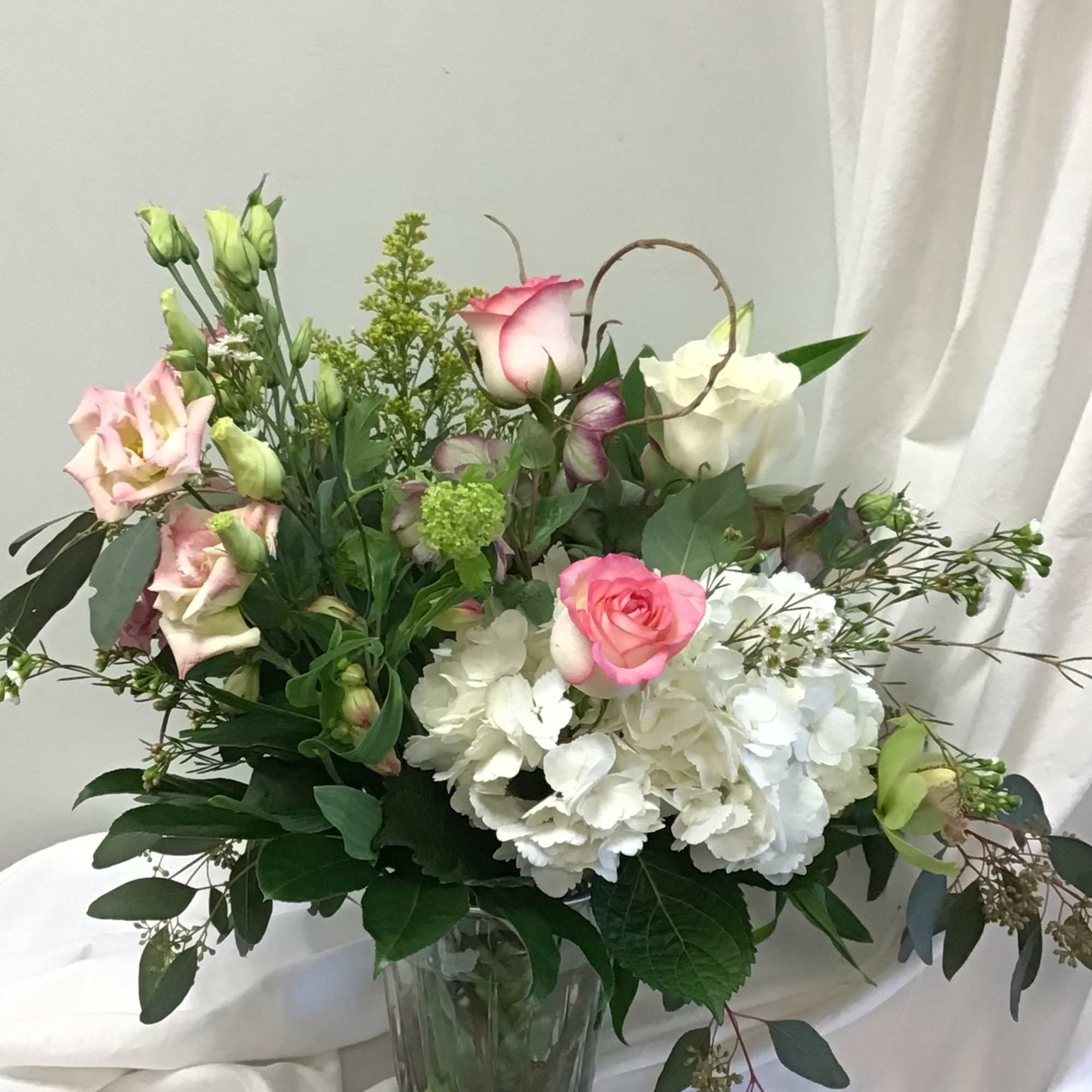 Pink and white roses with white hydrangeas in a glass vase