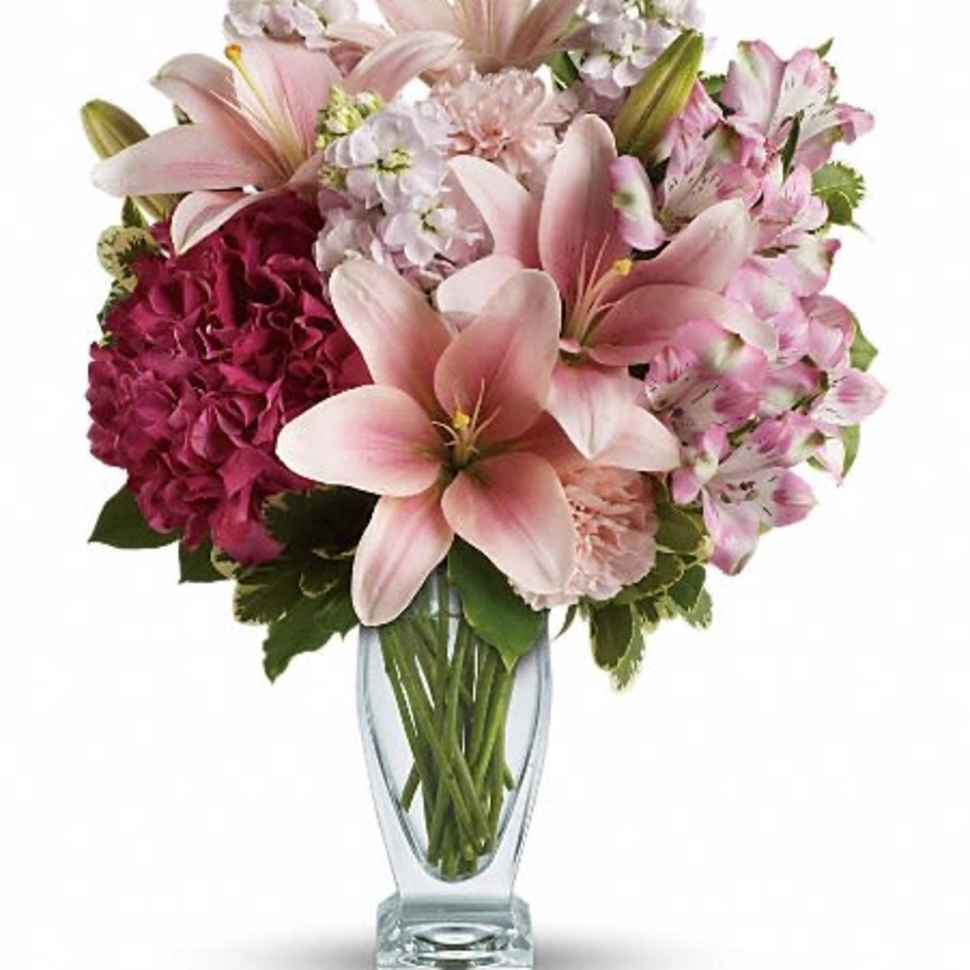 Pink lilies and mixed blooms arranged in a clear glass vase