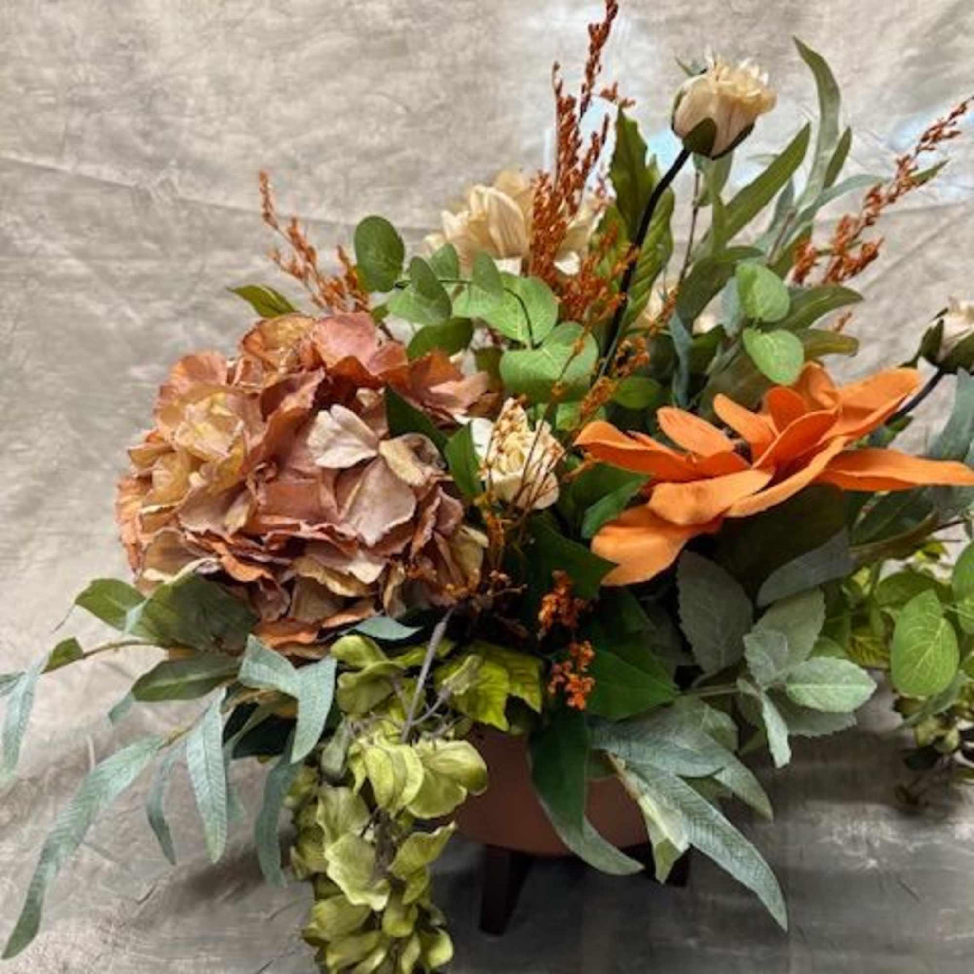 Autumn floral arrangement with hydrangea and orange blooms in a vase