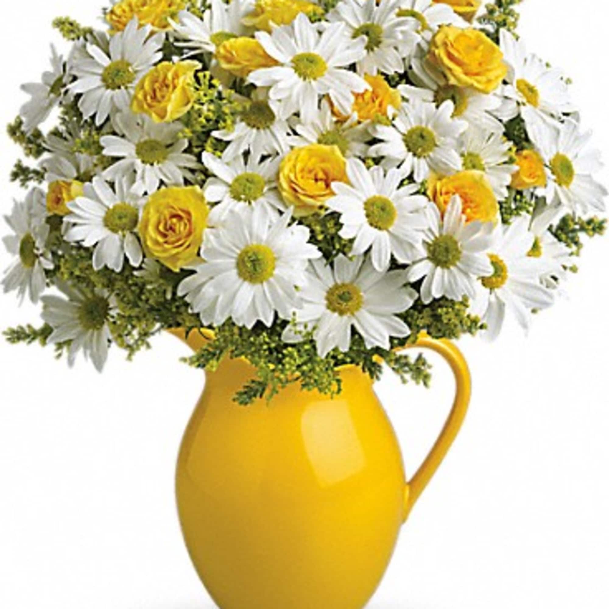 Yellow pitcher vase holding white daisies and yellow roses