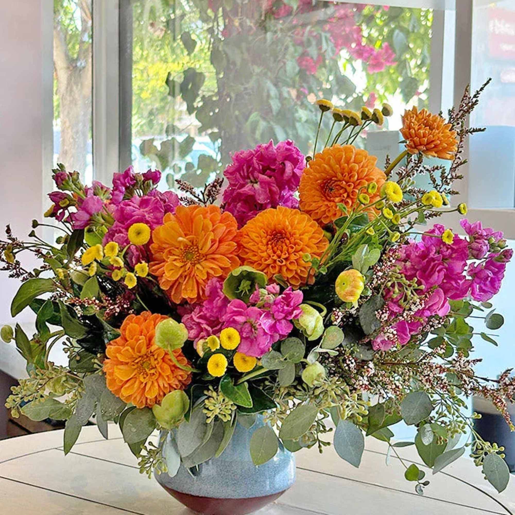 Bright mixed flower arrangement in a blue vase with orange and pink blooms