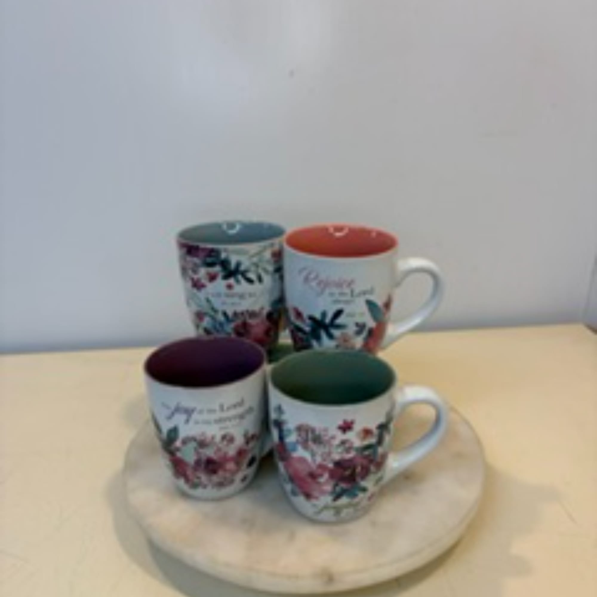 Four floral-patterned ceramic mugs arranged on a round tray