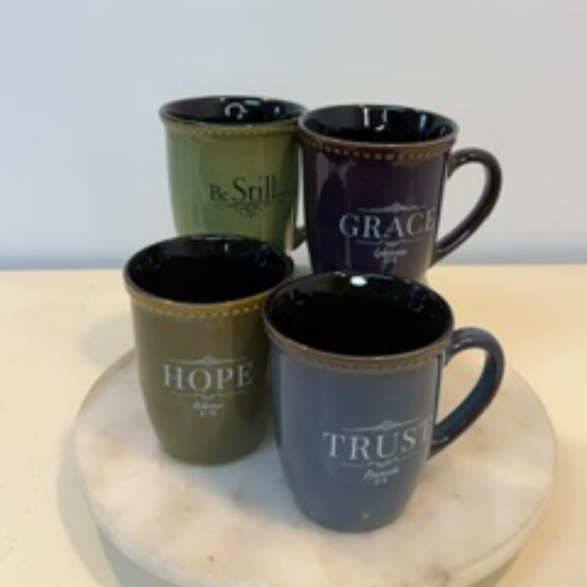 Four decorative mugs with inspirational words on a round tray