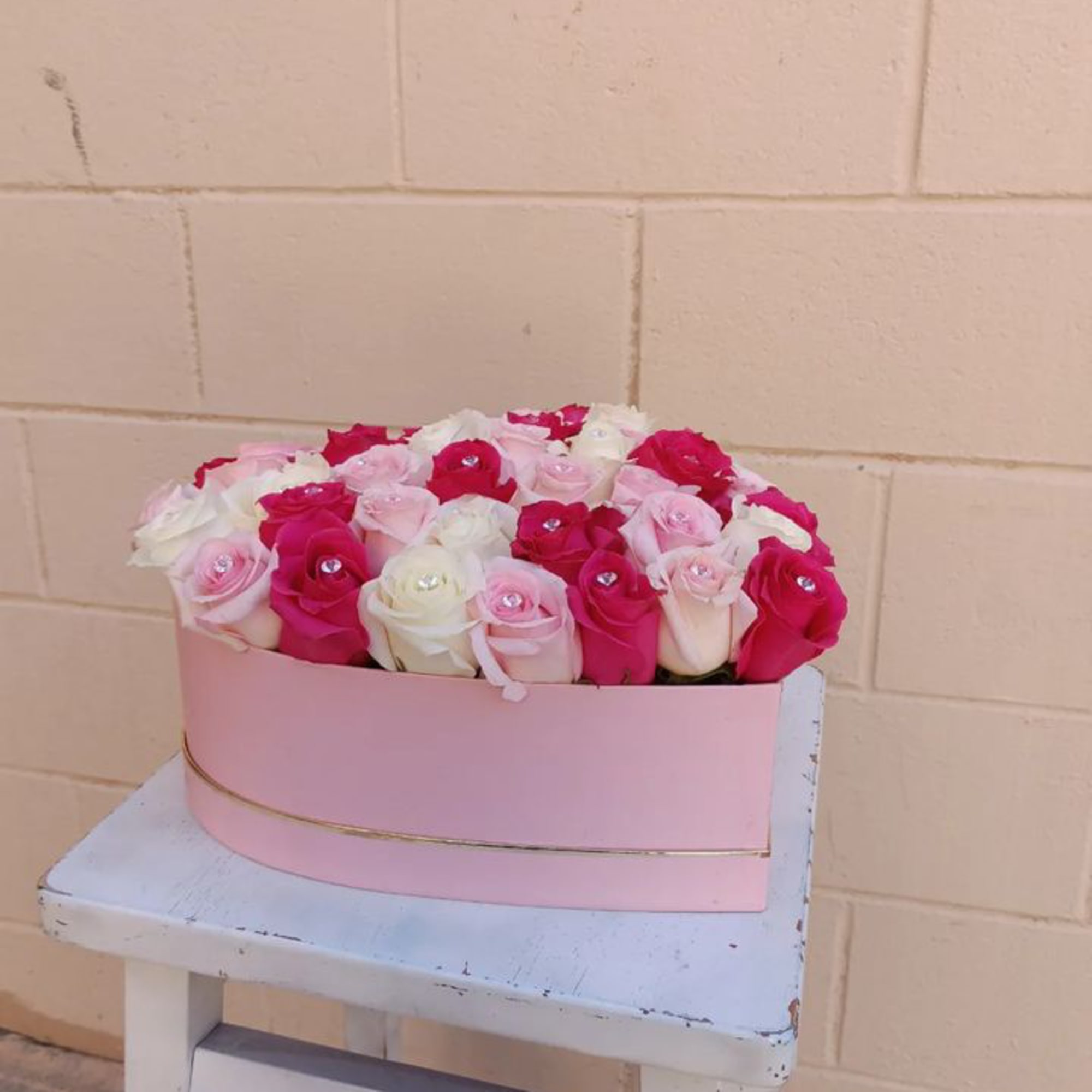 Pink and white roses arranged in a pink hat box