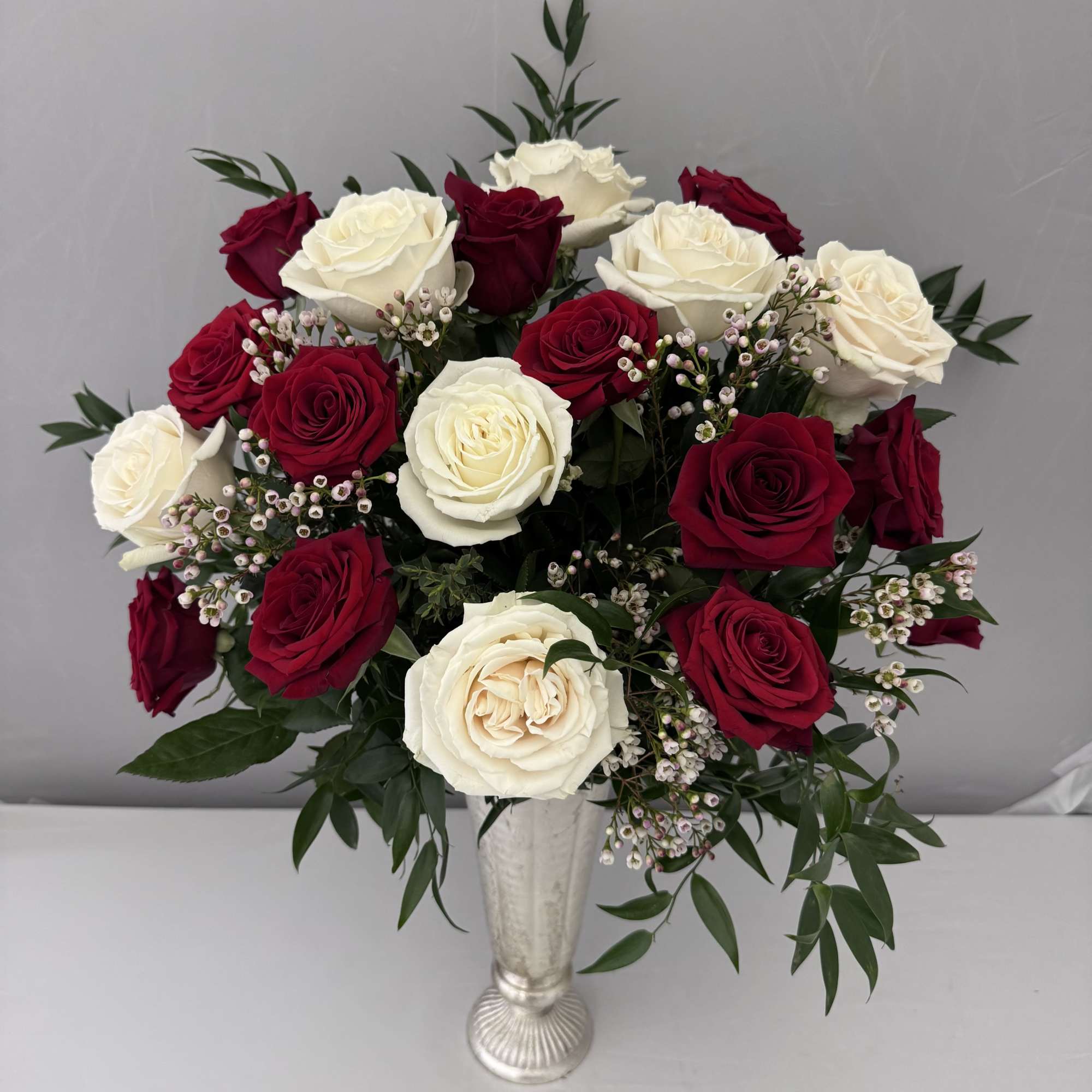 Red and white roses arranged in a silver vase