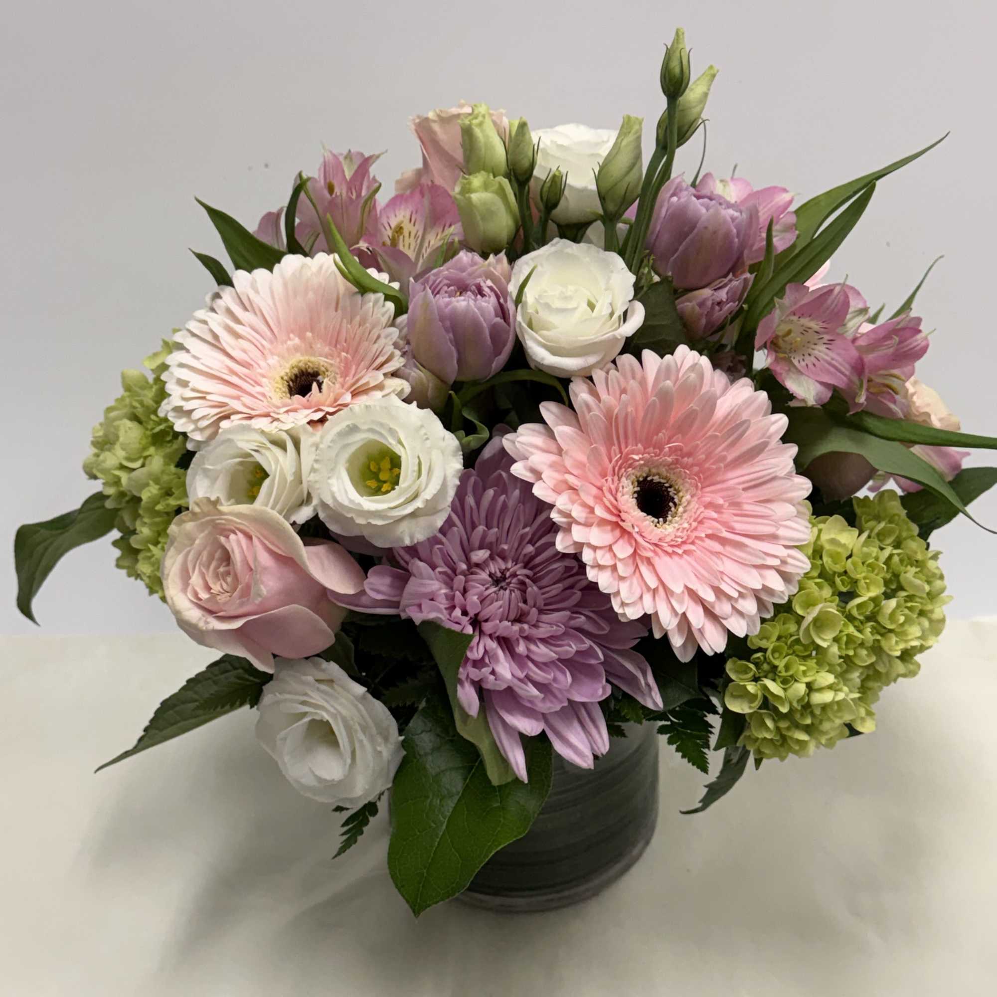 A lovely combination of pastels arranged in a compact pink gerberas, roses