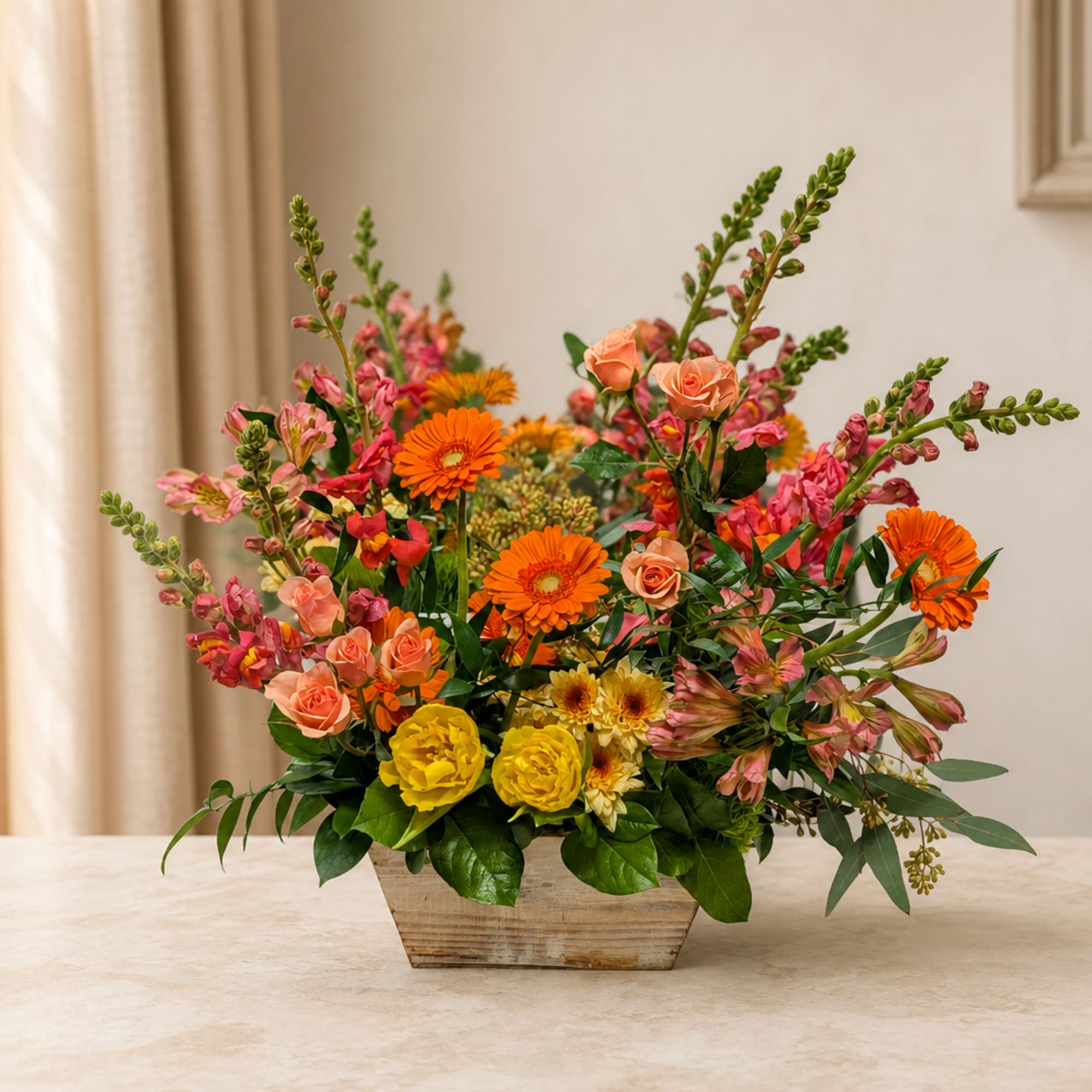 Mixed bouquet of orange, pink, and yellow flowers in a wooden container