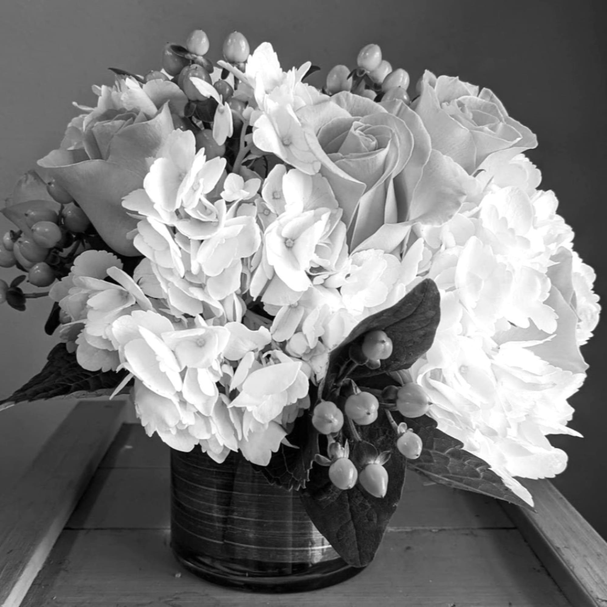 White floral arrangement with roses and hydrangeas in a dark vase