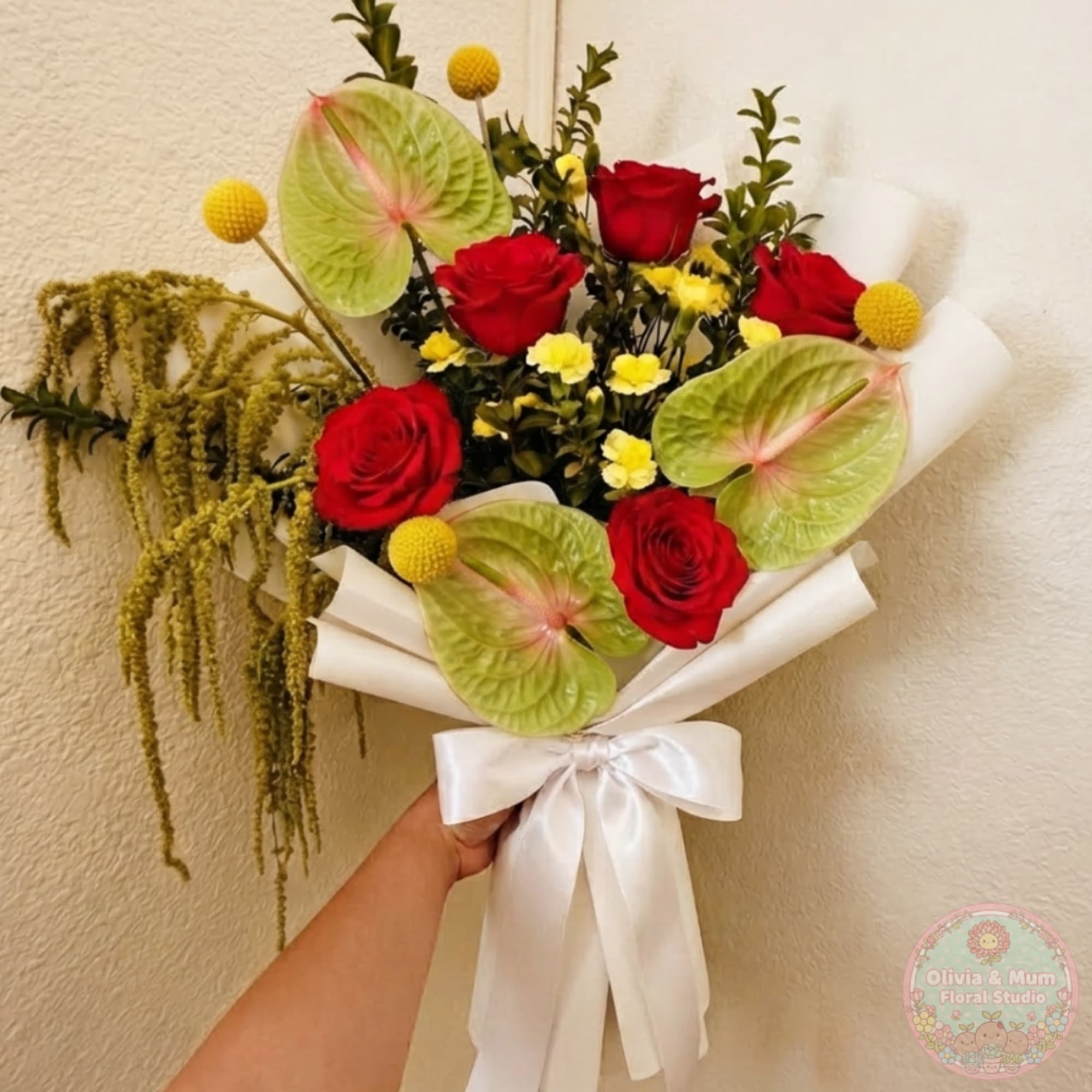 Bouquet of red roses with green anthuriums and yellow accents, tied with a white ribbon
