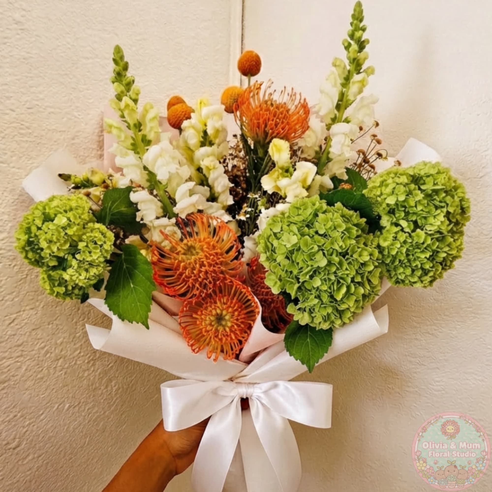 Hand-tied bouquet with green hydrangeas, white snapdragons, and orange pincushion blooms