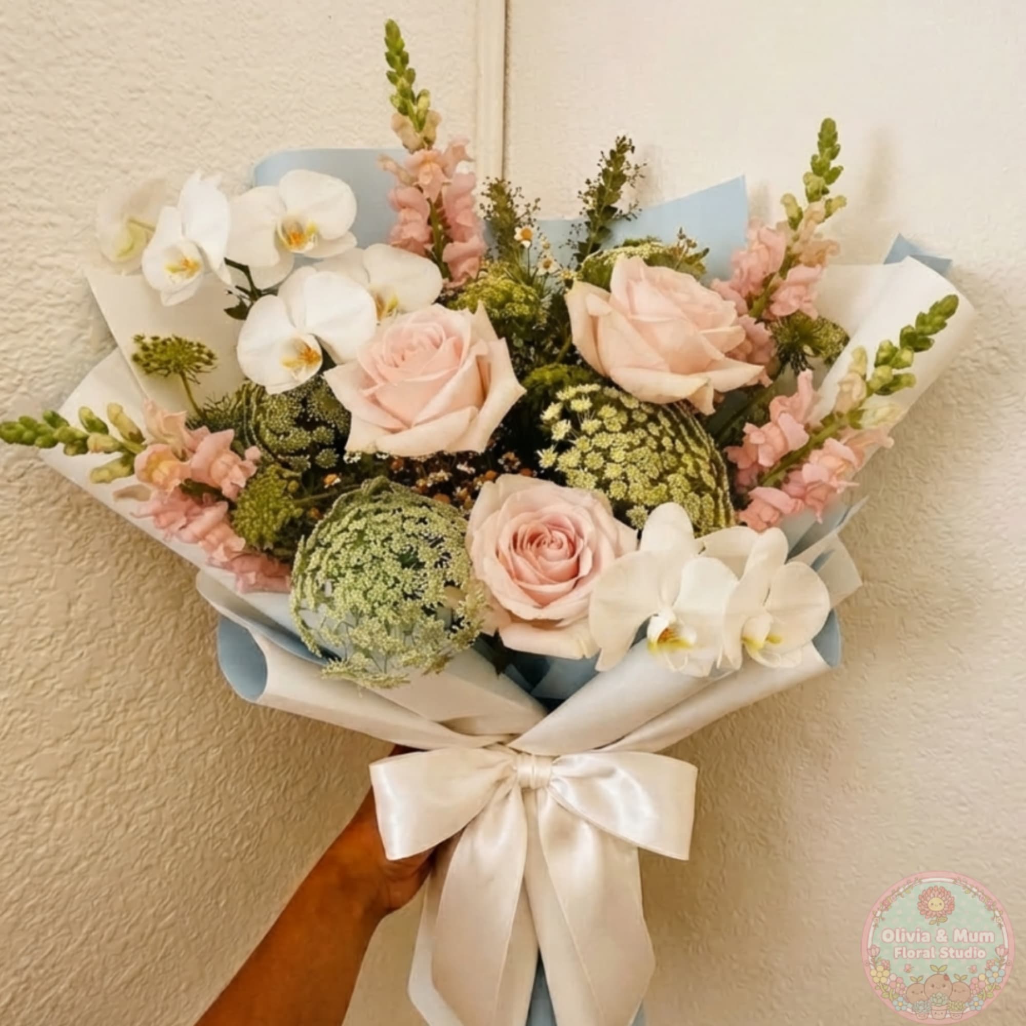 Handheld bouquet of pale pink roses and white orchids with a satin ribbon