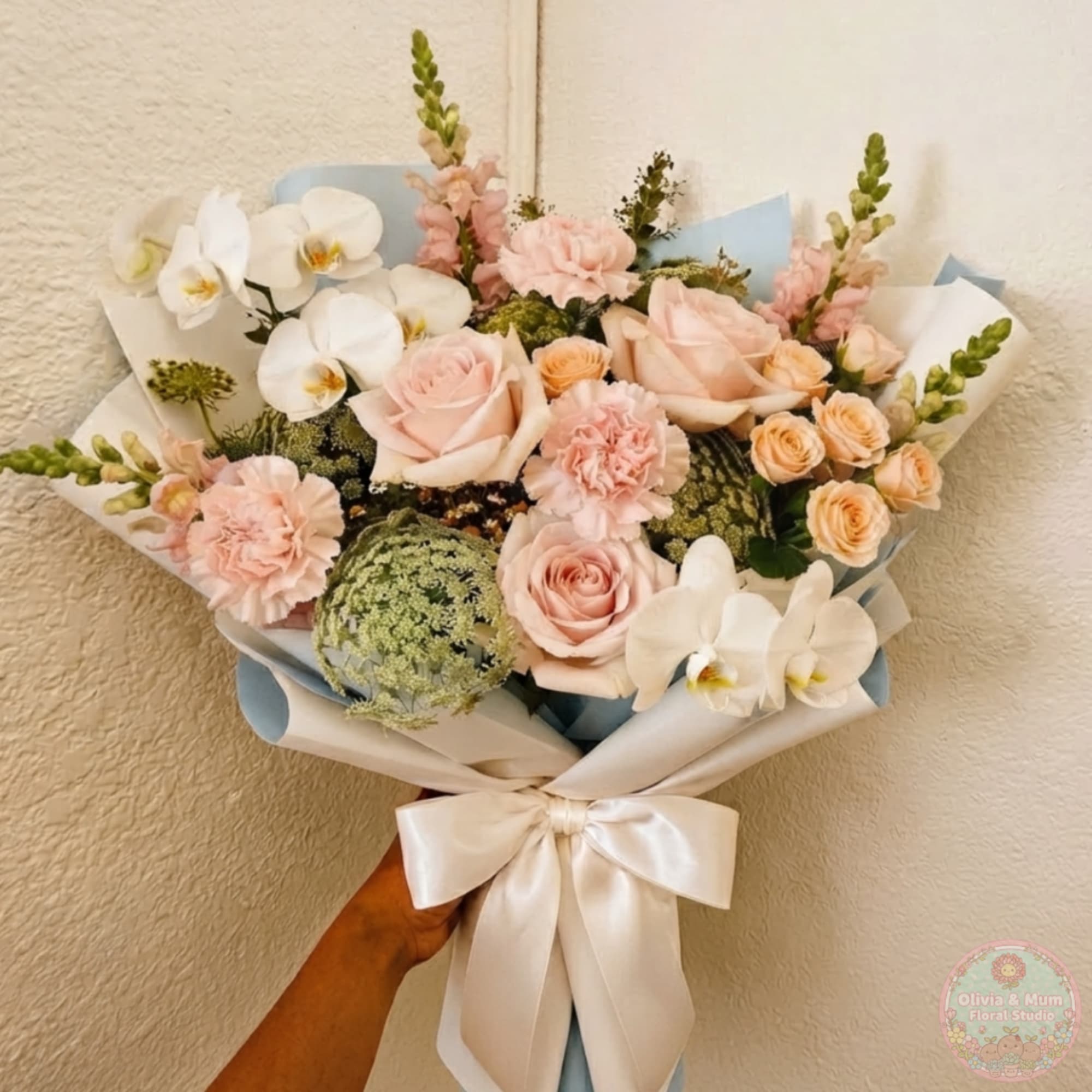 Bouquet of pale pink roses, white orchids, and peach spray roses with a satin bow