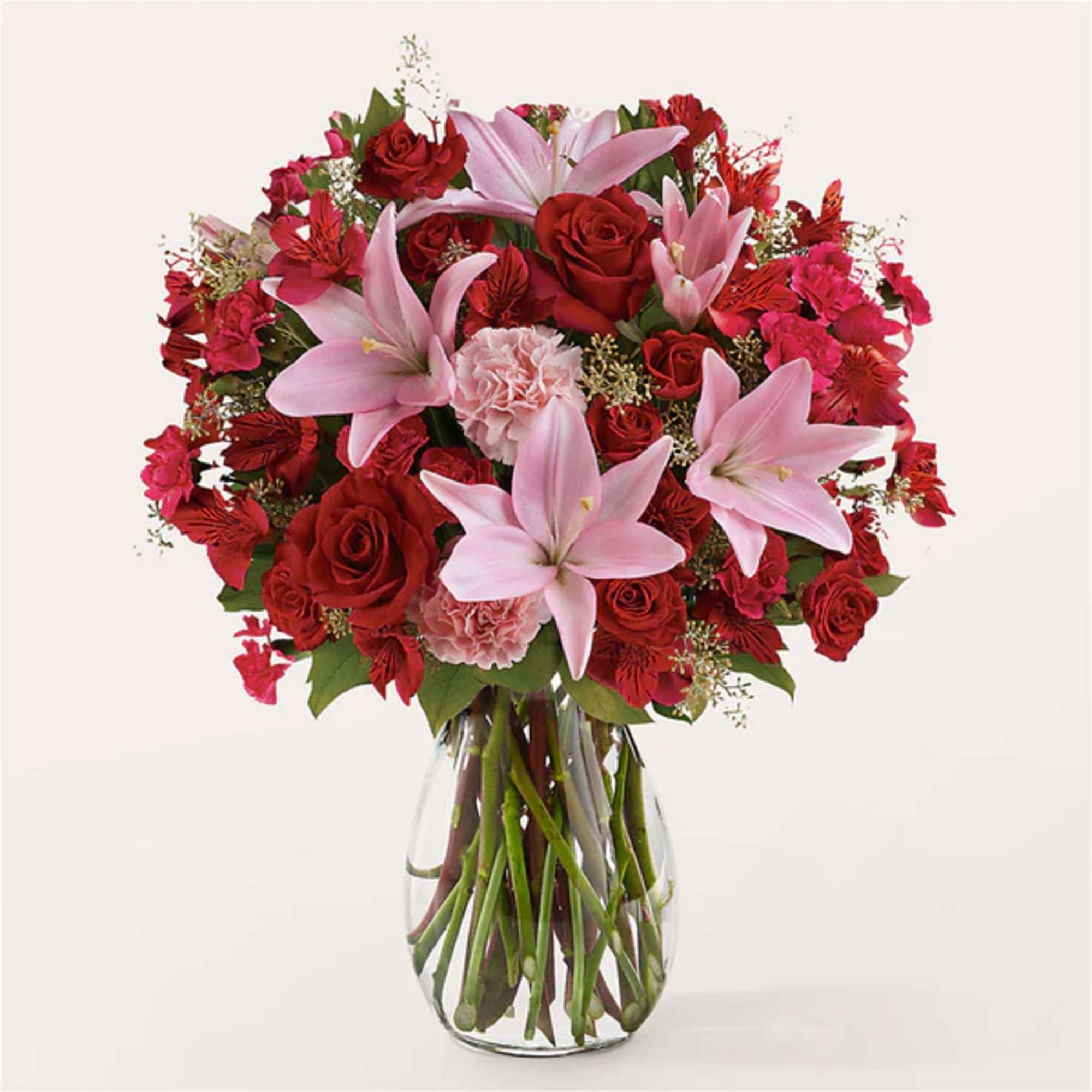 Bouquet of red roses, pink lilies, and carnations in a glass vase